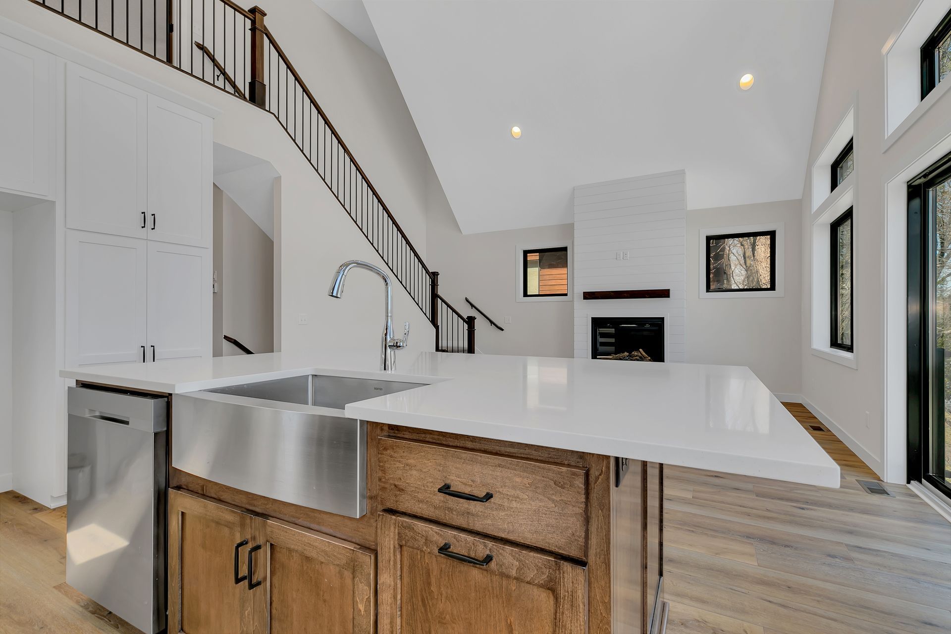 A kitchen with a stainless steel sink , wooden cabinets , and white counter tops.