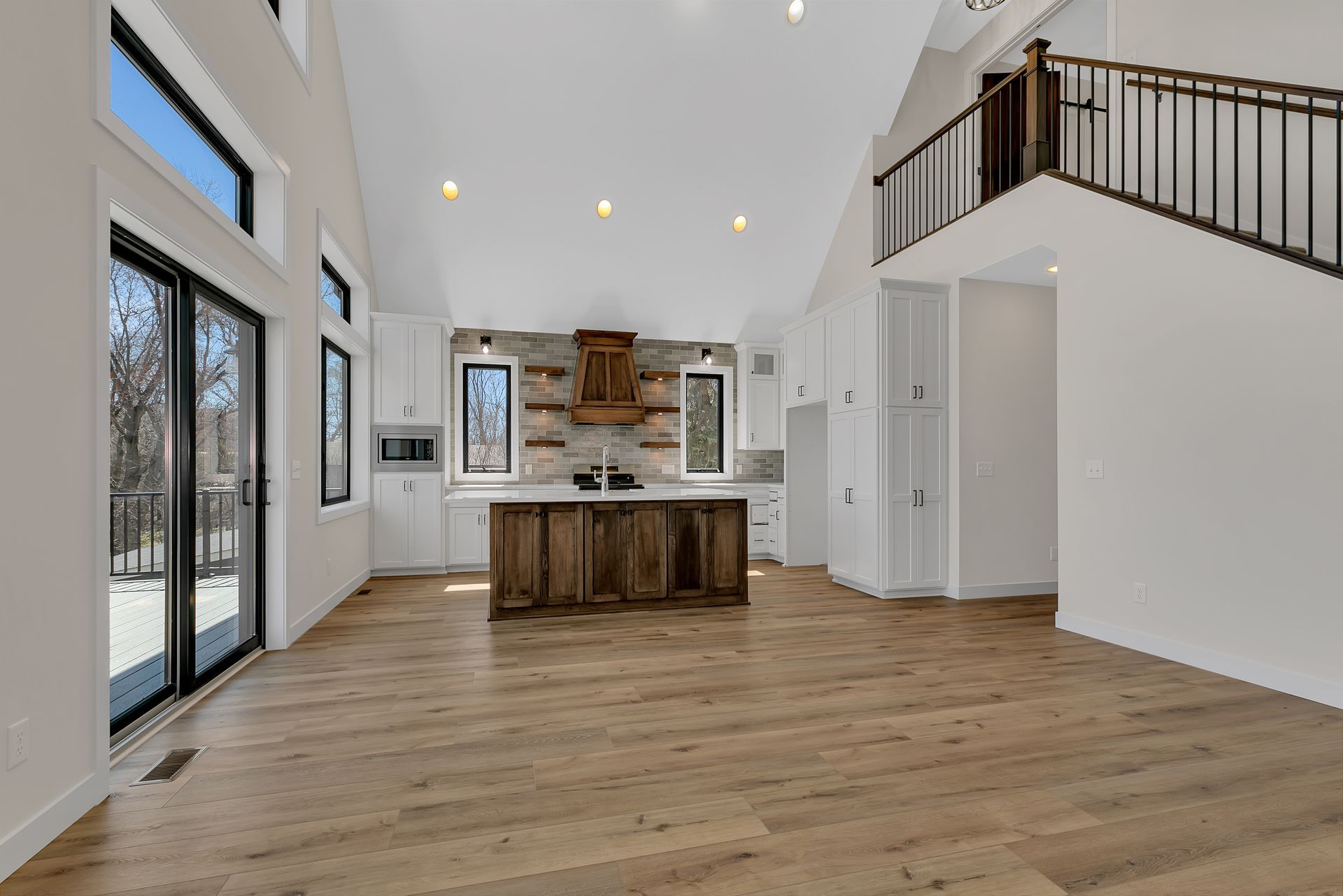 A large empty room with hardwood floors and a kitchen.