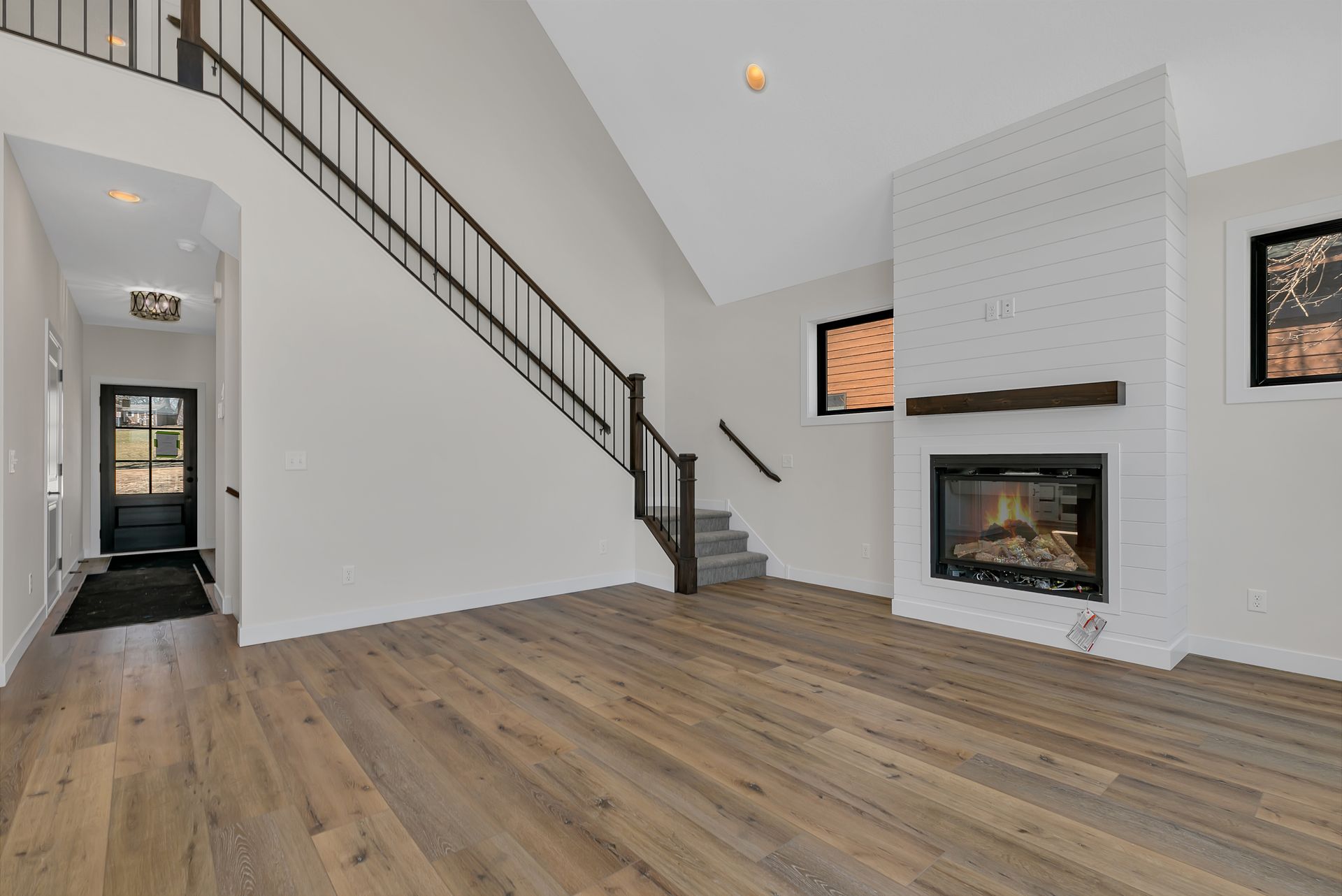 A living room with hardwood floors , a fireplace and stairs.