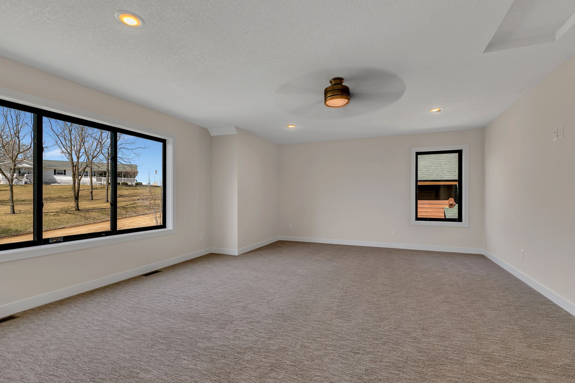 An empty room with a ceiling fan and two windows