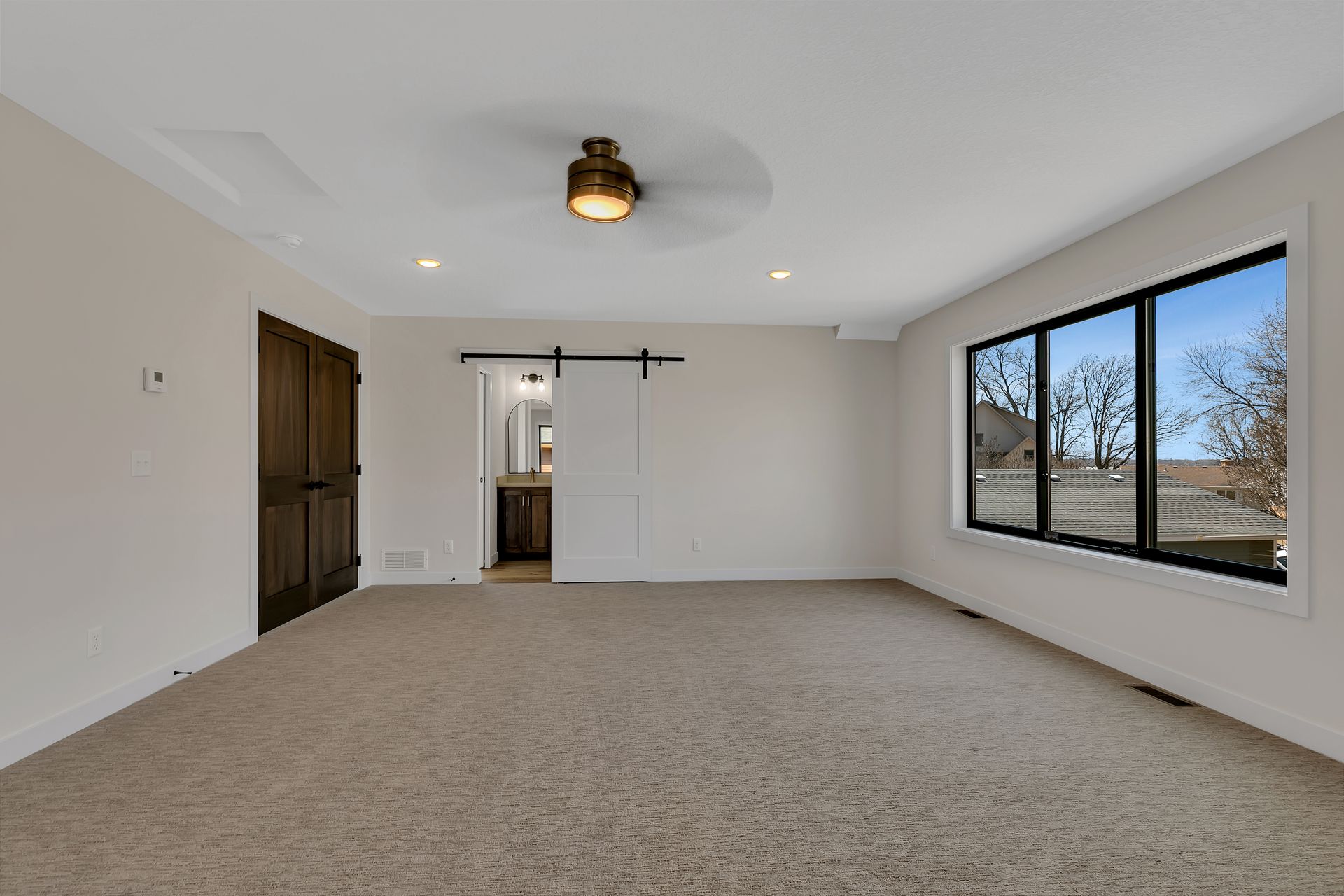 An empty room with a ceiling fan and a sliding barn door.