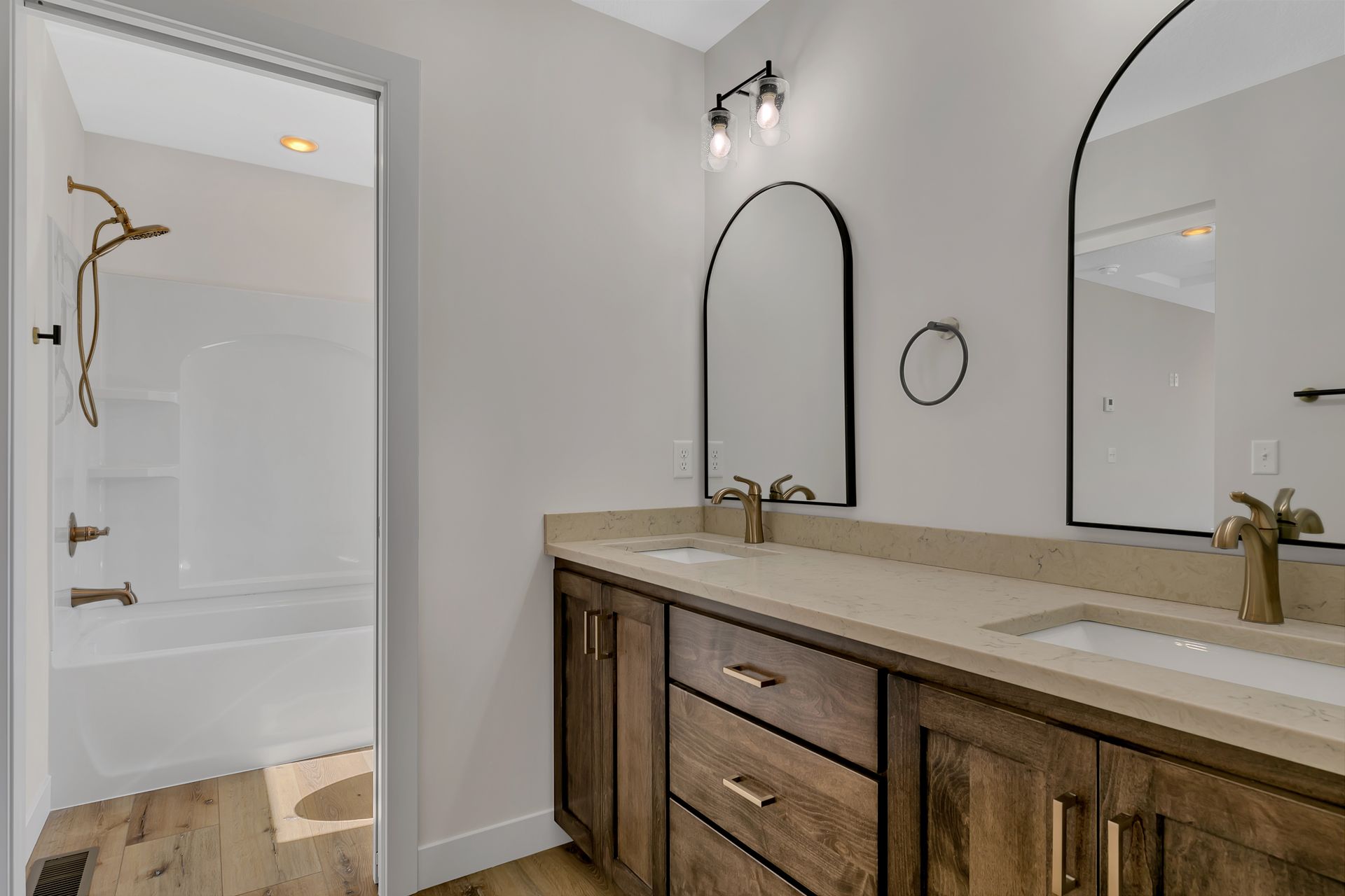 A bathroom with two sinks , two mirrors and a bathtub.
