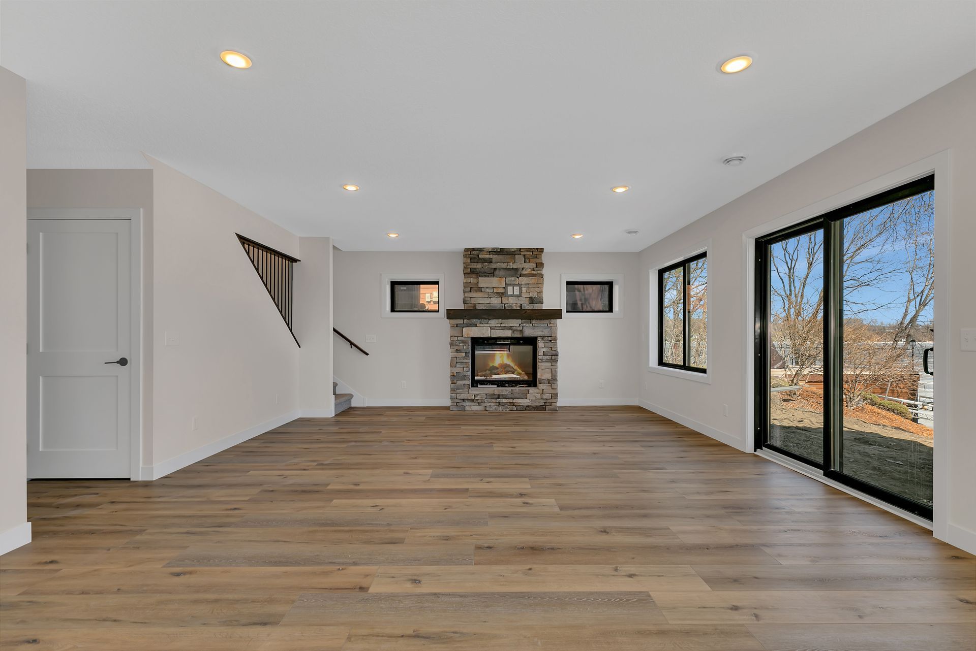 An empty living room with a fireplace and sliding glass doors.