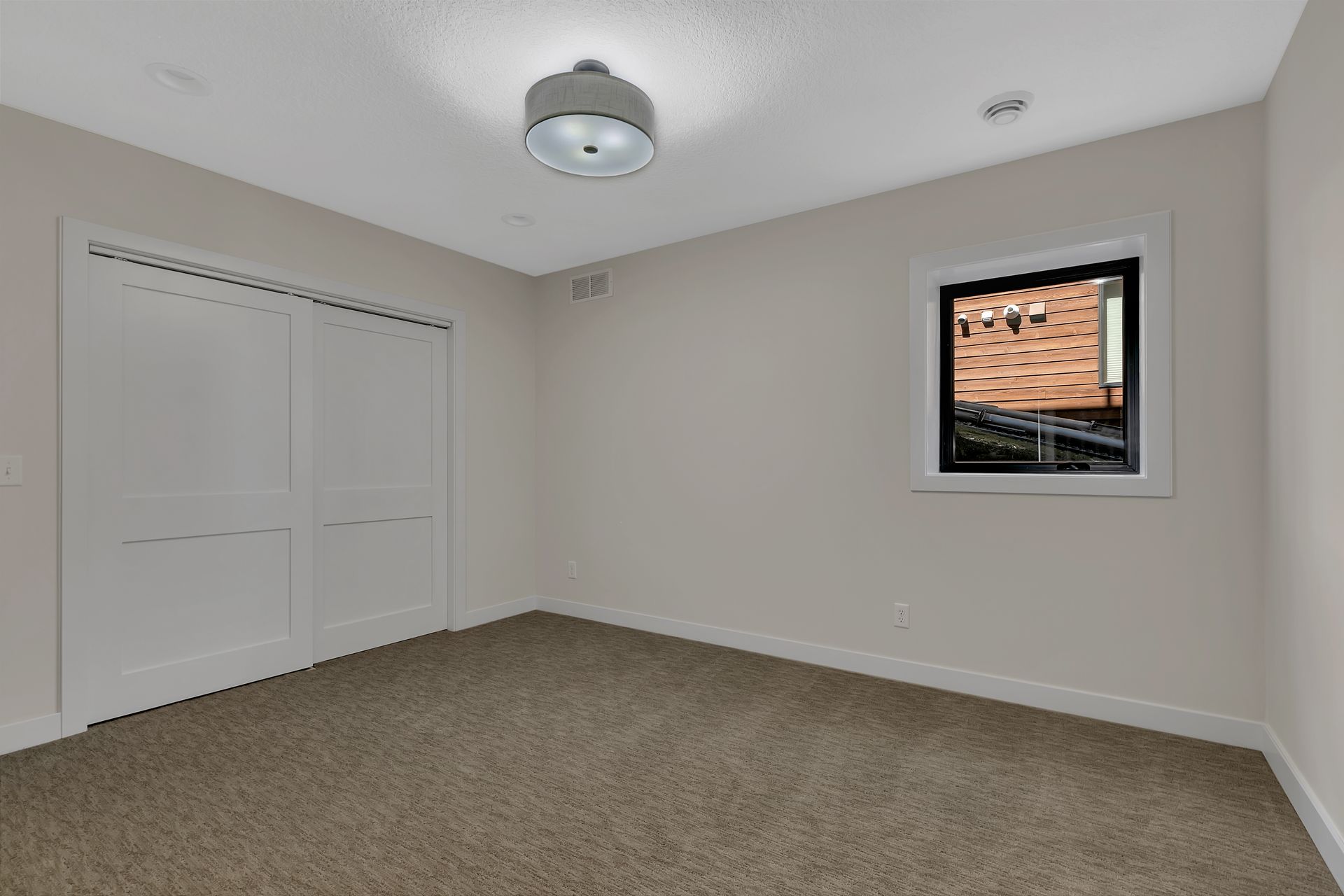 An empty room with a carpeted floor and a window.