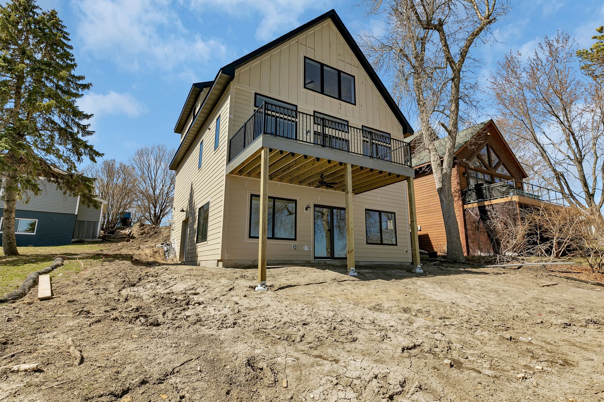 A large house with a deck is sitting on top of a dirt hill.