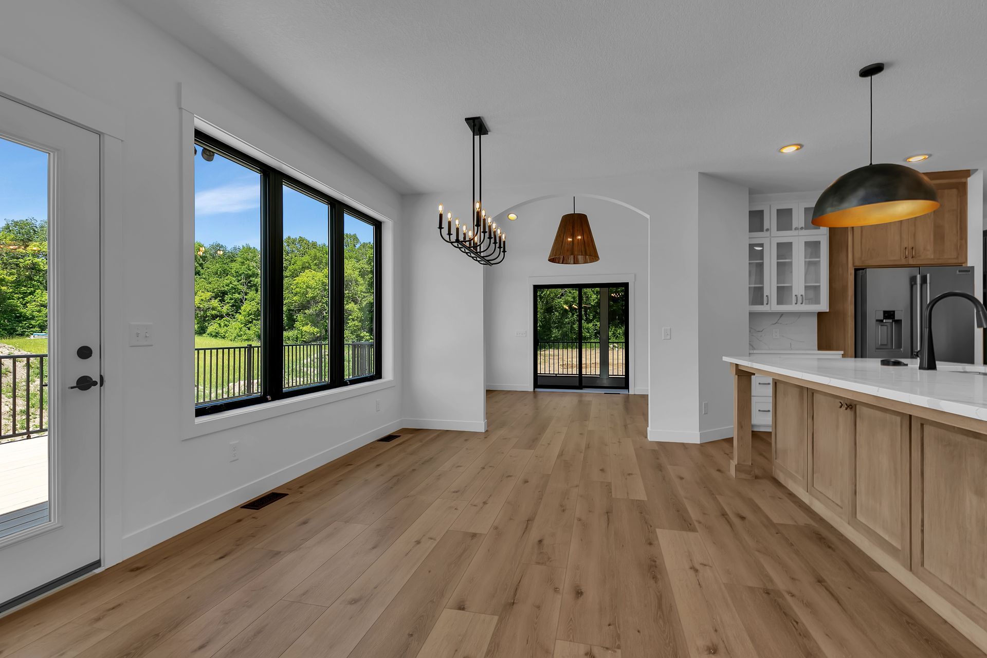 A large empty room with hardwood floors and a kitchen.
