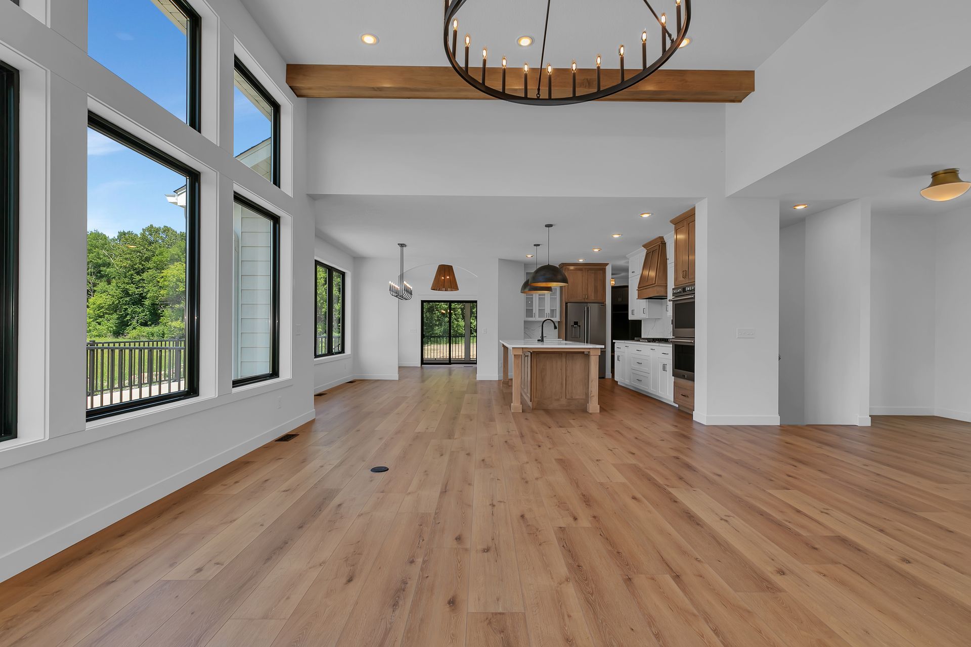 A large empty room with hardwood floors and a chandelier.