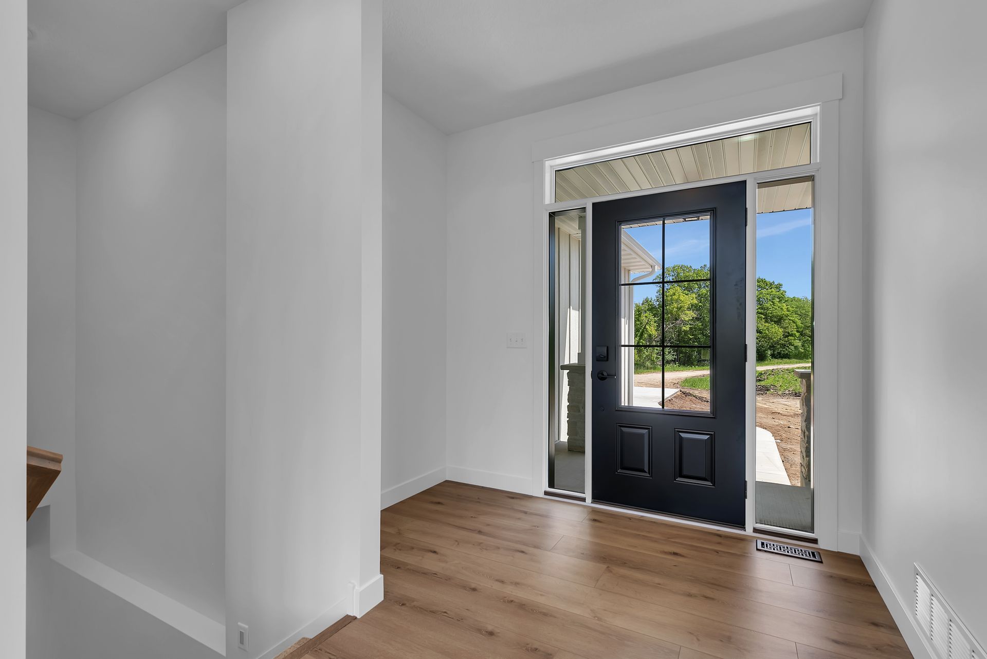 An empty hallway with a black door and a wooden floor.