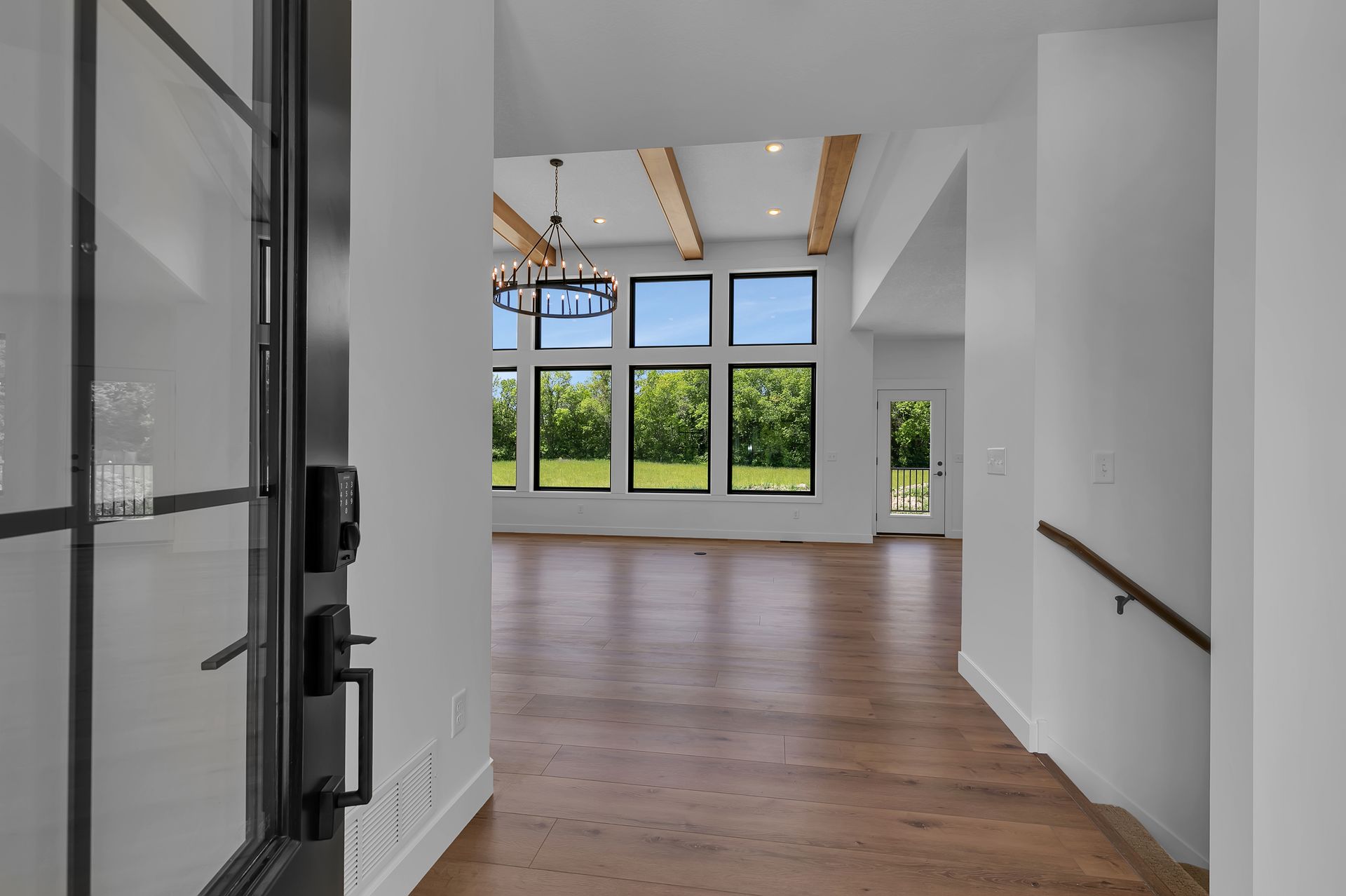 A hallway in a house with a black door and wooden floors.