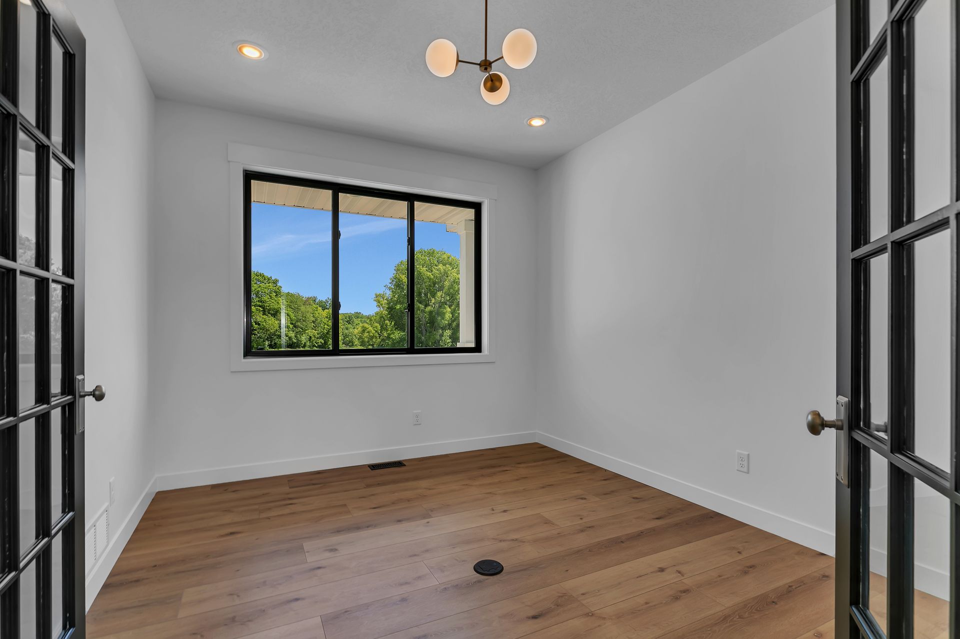 An empty room with hardwood floors and a large window.