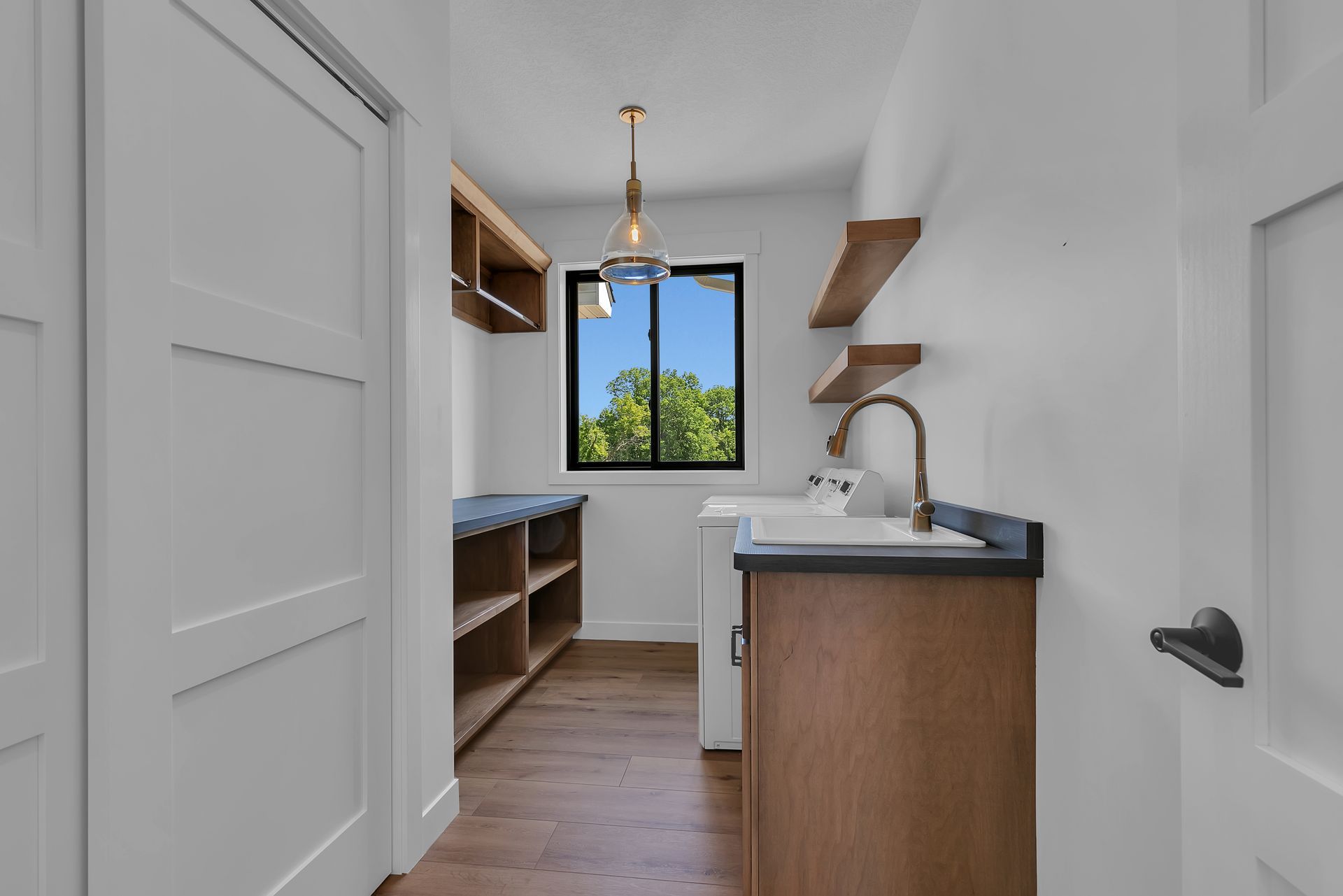 A laundry room with a sink , washer and dryer , and a window.
