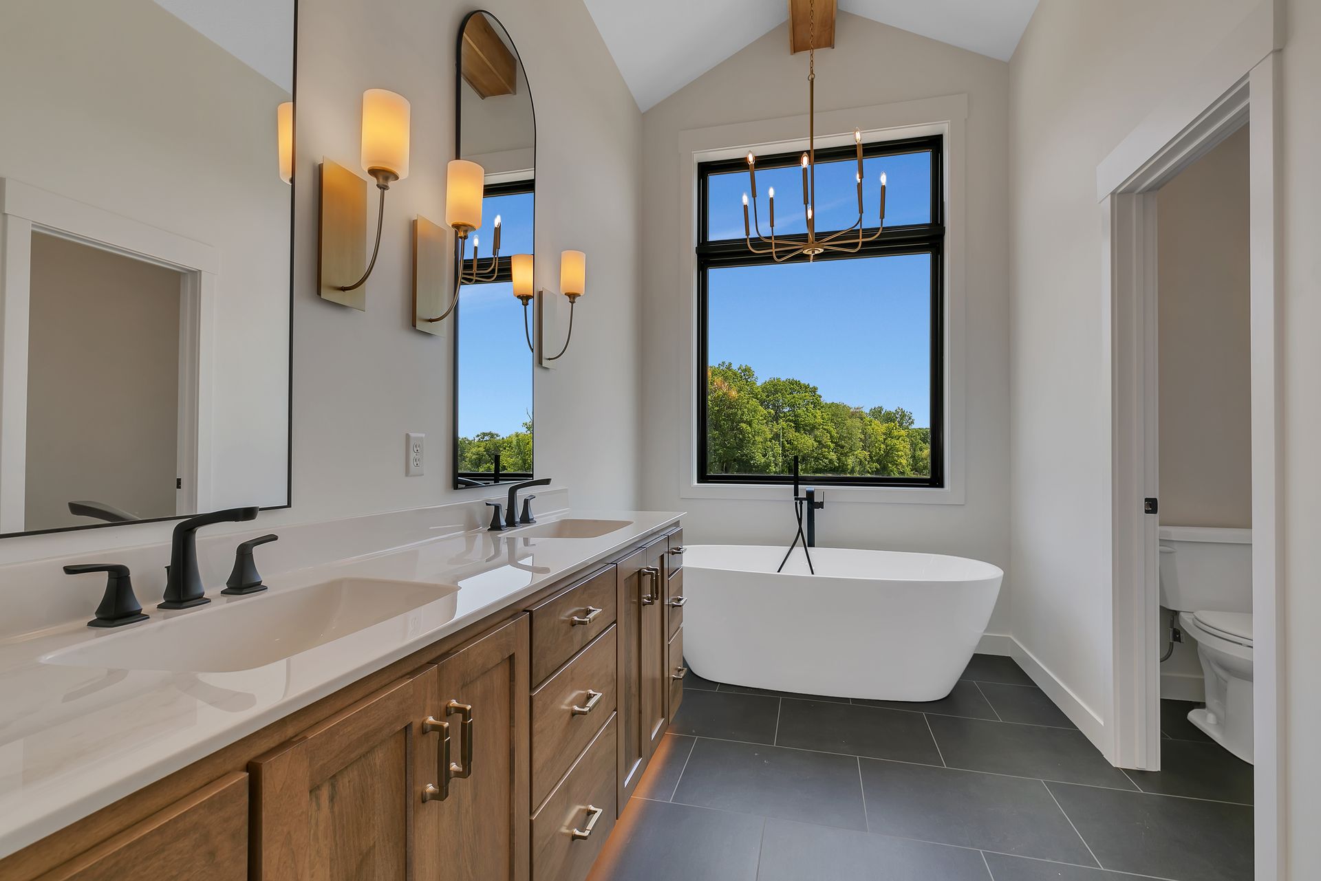 A bathroom with two sinks , a tub and a window