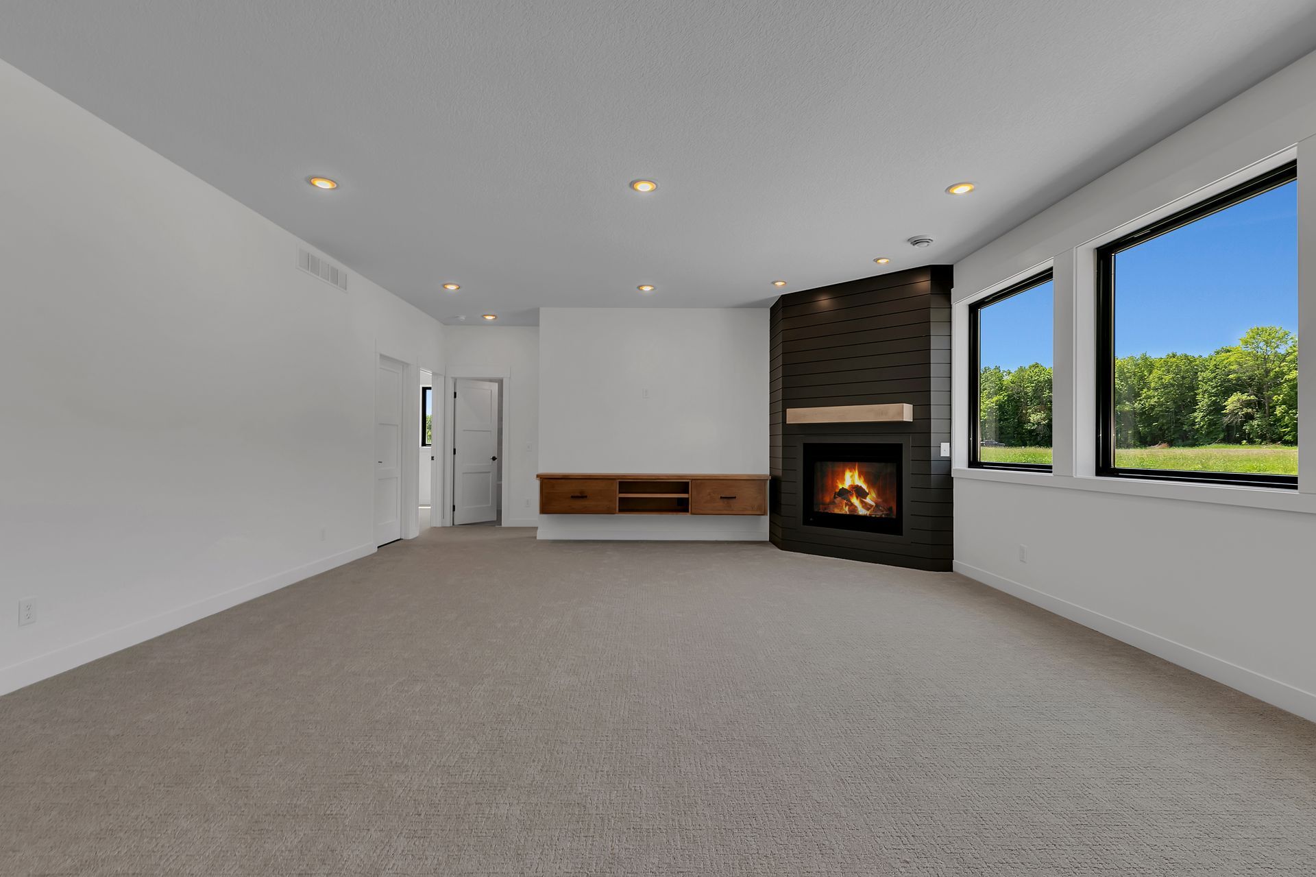 An empty living room with a fireplace and two windows.