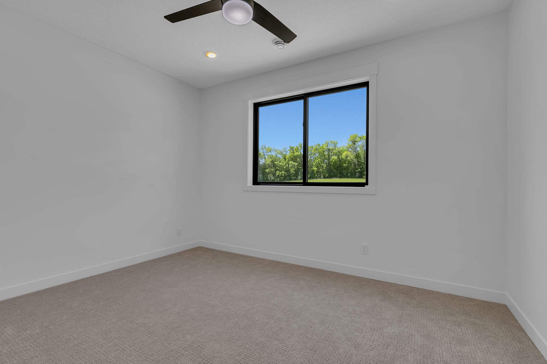 An empty bedroom with a ceiling fan and a window.