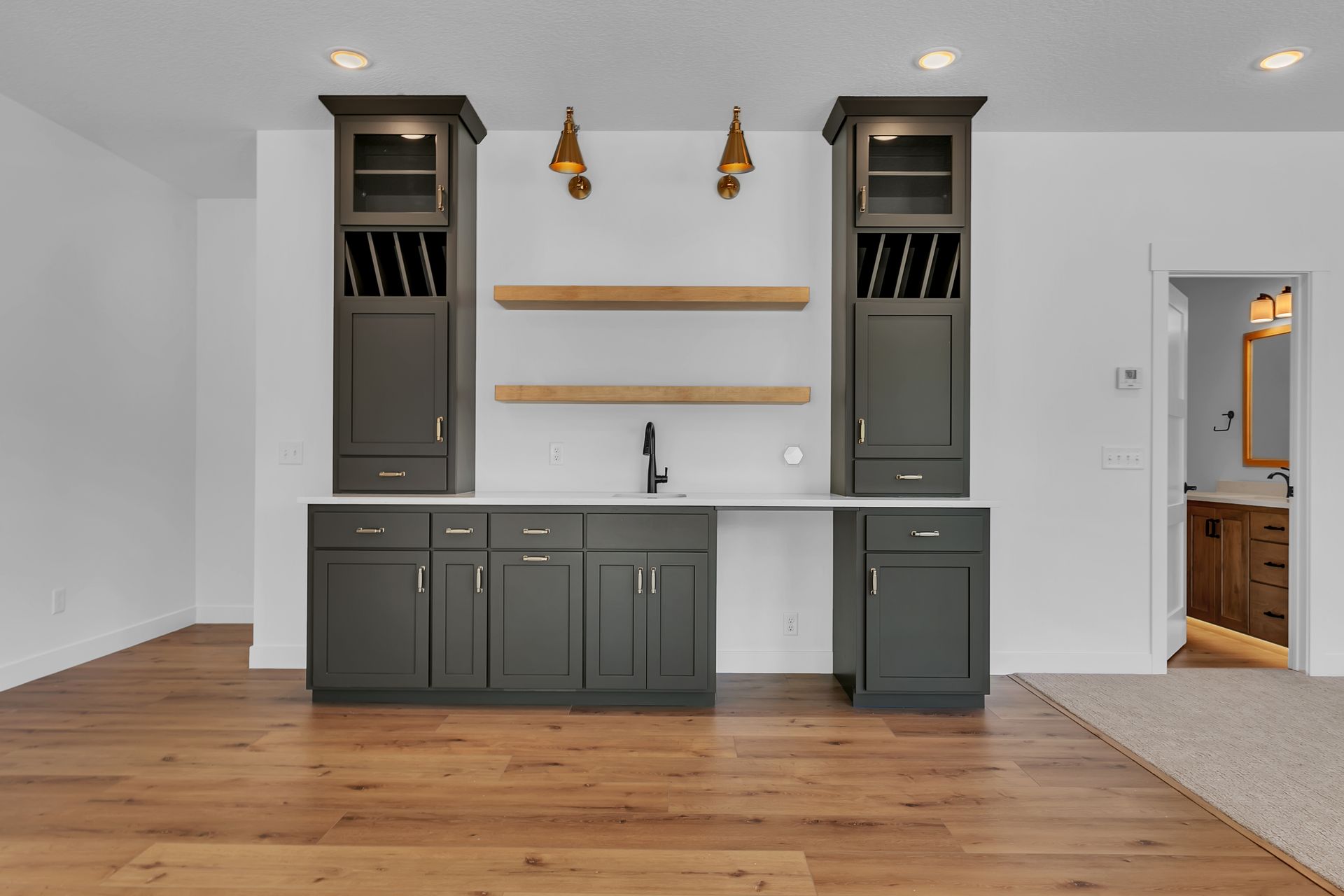A kitchen with gray cabinets and wooden floors and a sink.