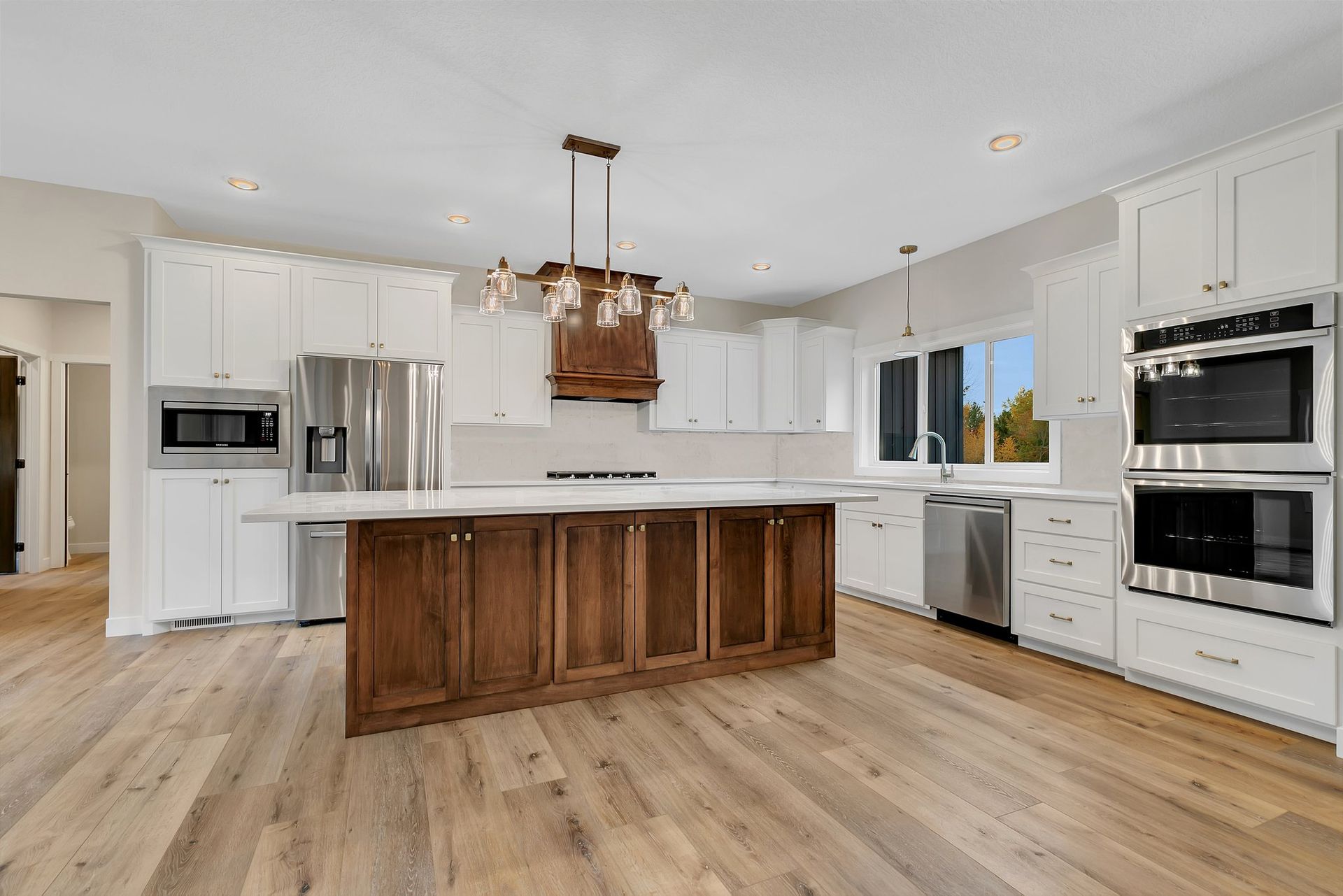A kitchen with white cabinets , stainless steel appliances , and a large island.