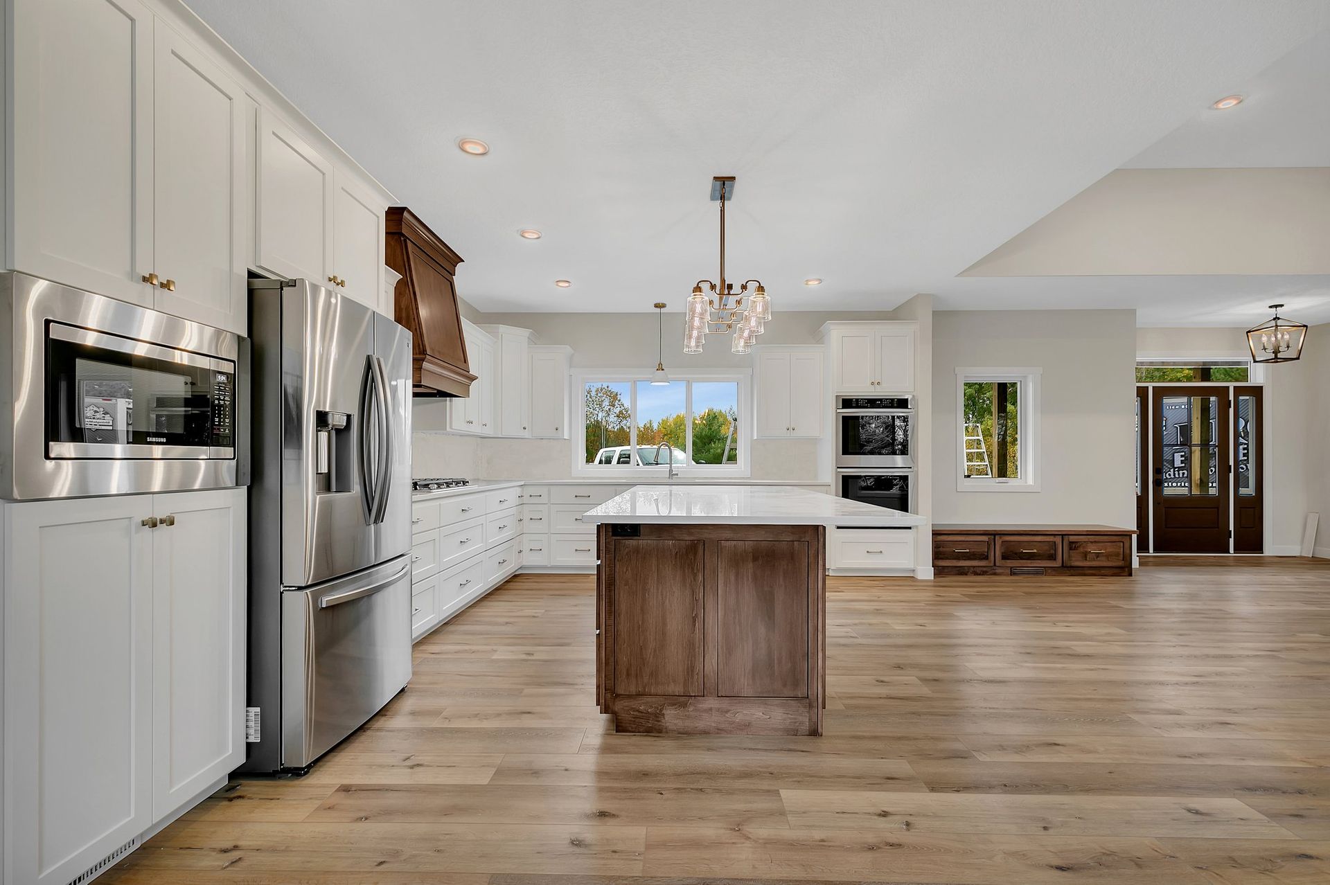 A kitchen with white cabinets , stainless steel appliances , and a large island.