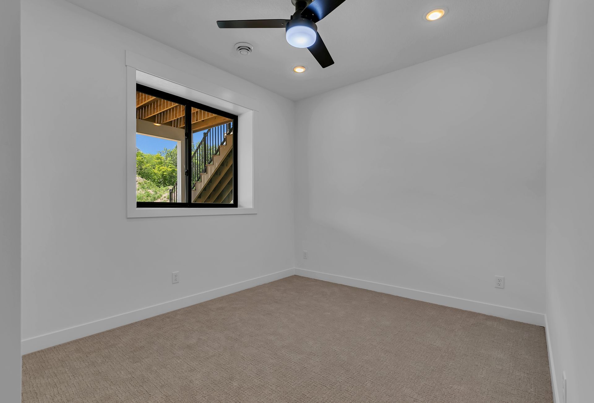 An empty bedroom with a ceiling fan and a window.