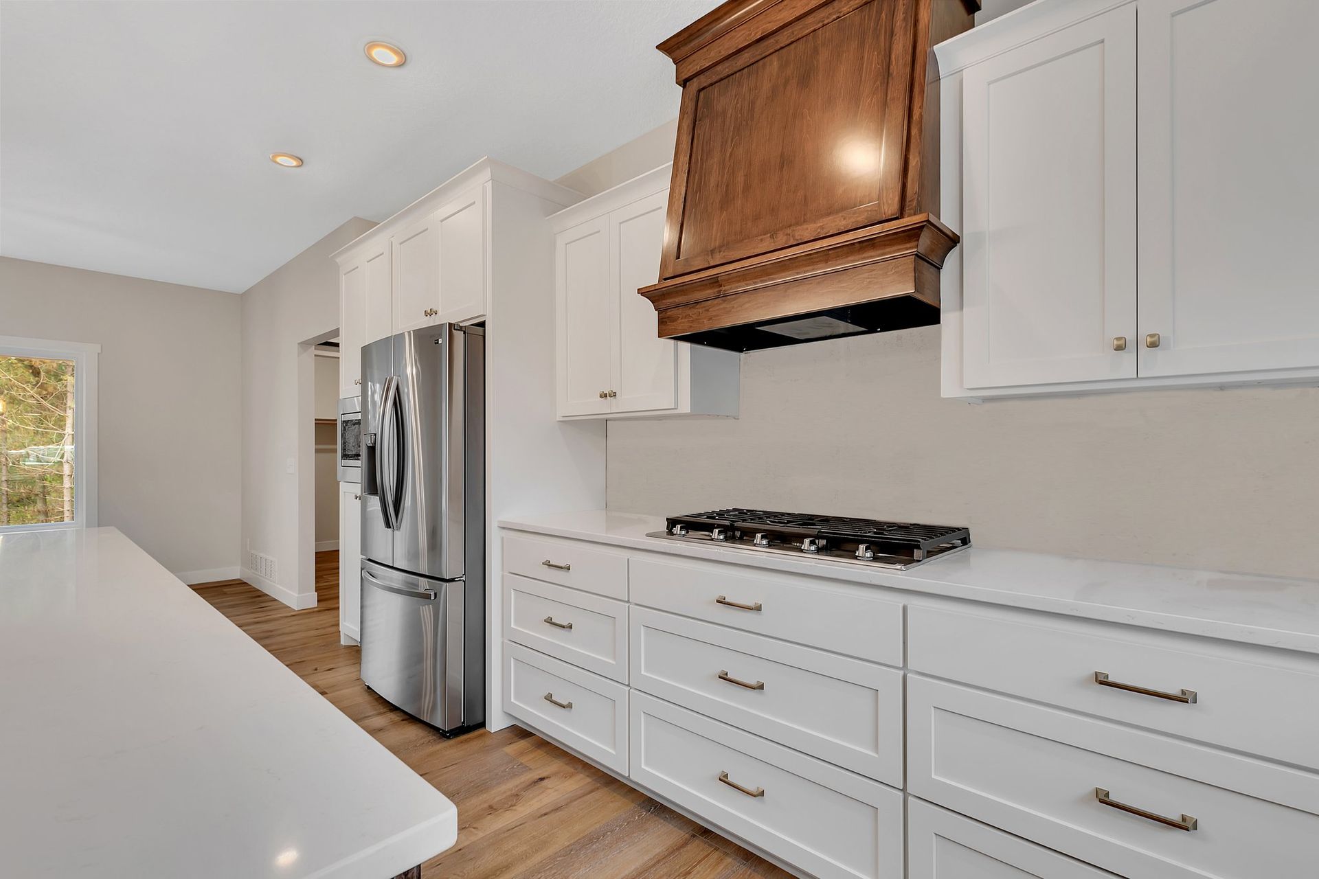 A kitchen with white cabinets , stainless steel appliances , a refrigerator and a stove top oven.