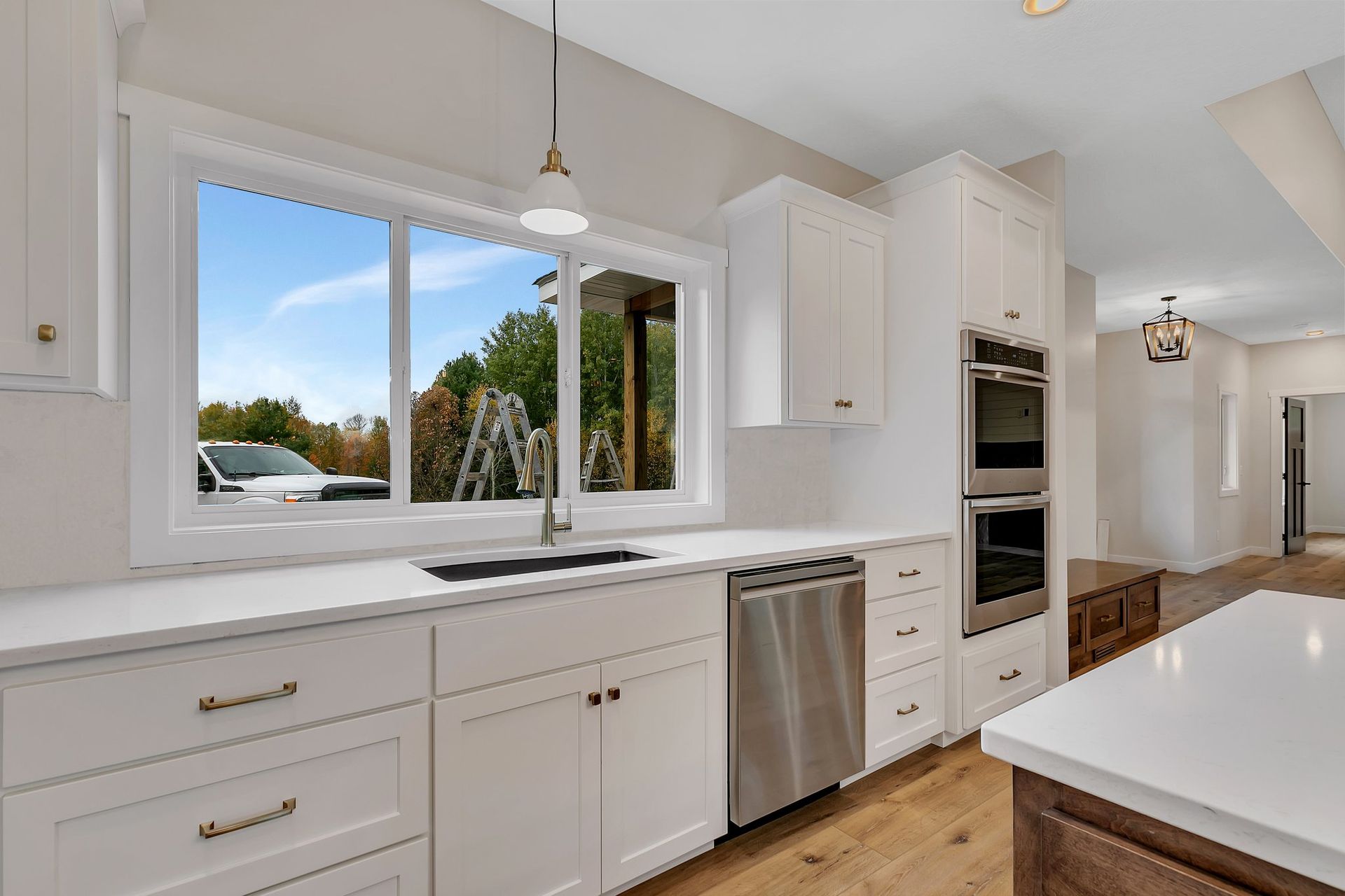 A kitchen with white cabinets , stainless steel appliances , and a large window.