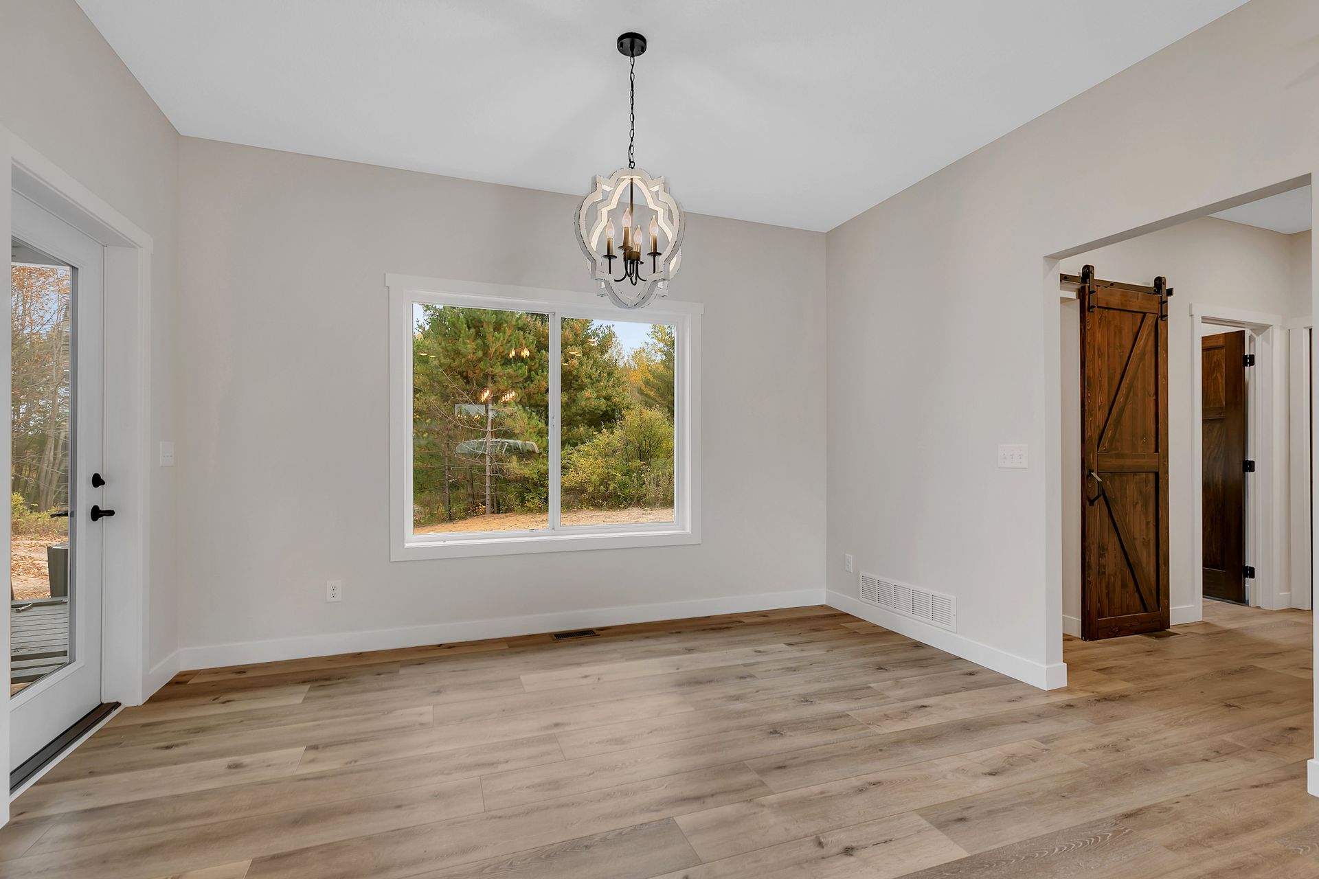 An empty living room with hardwood floors and a large window.