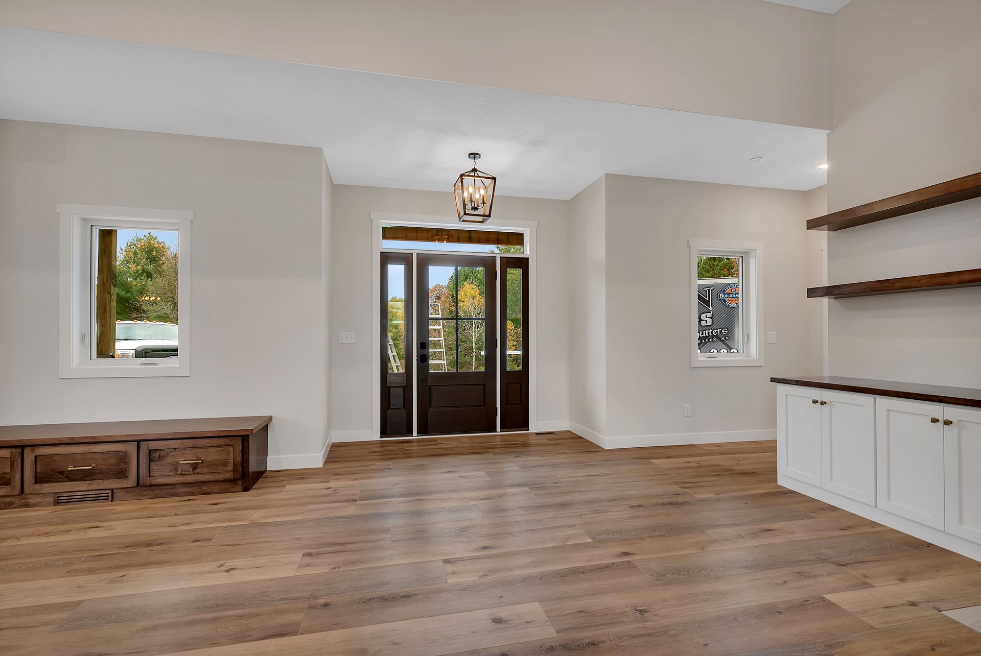 An empty living room with hardwood floors and white cabinets.
