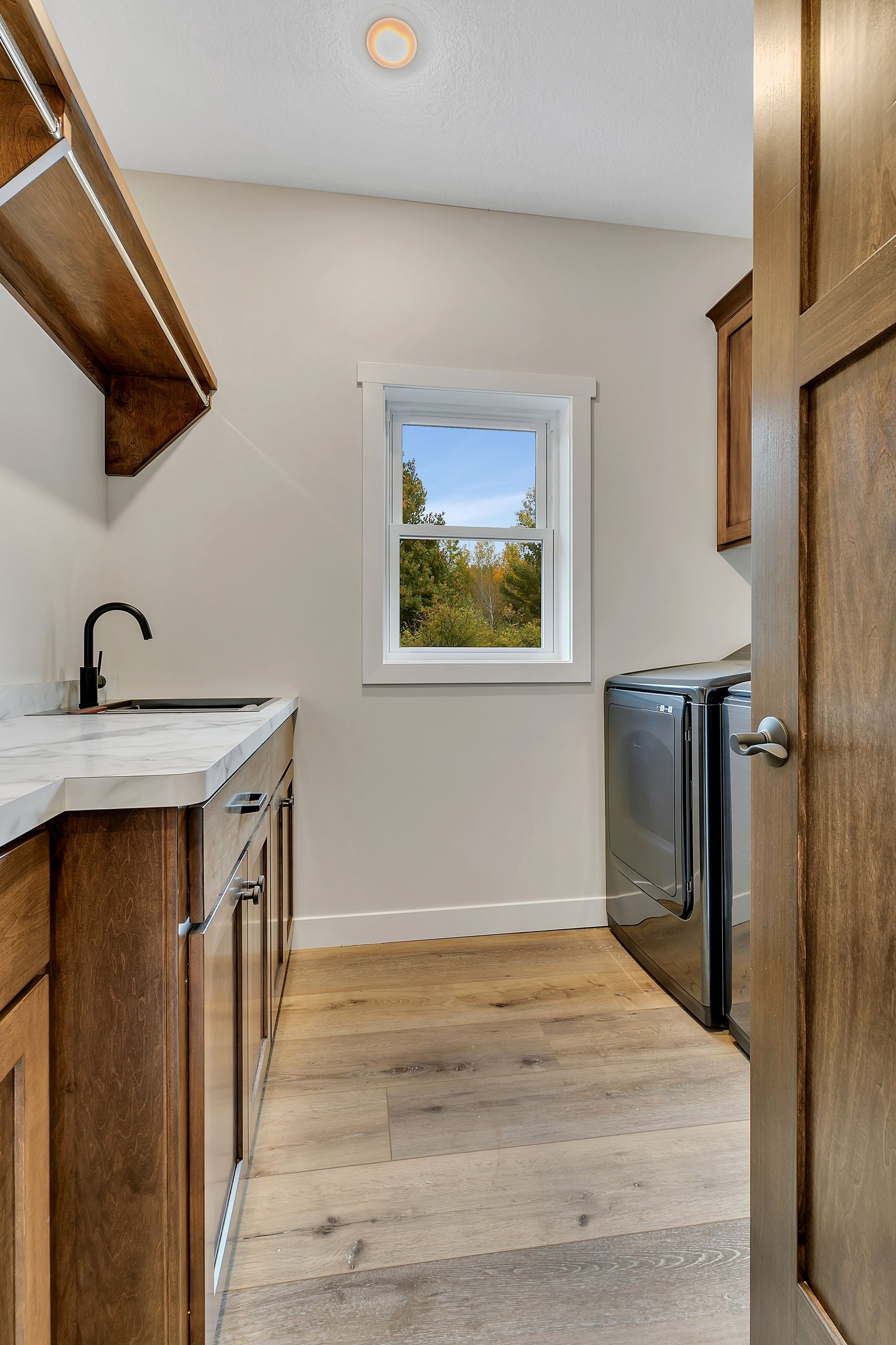 A laundry room with a sink , washer and dryer , and a window.