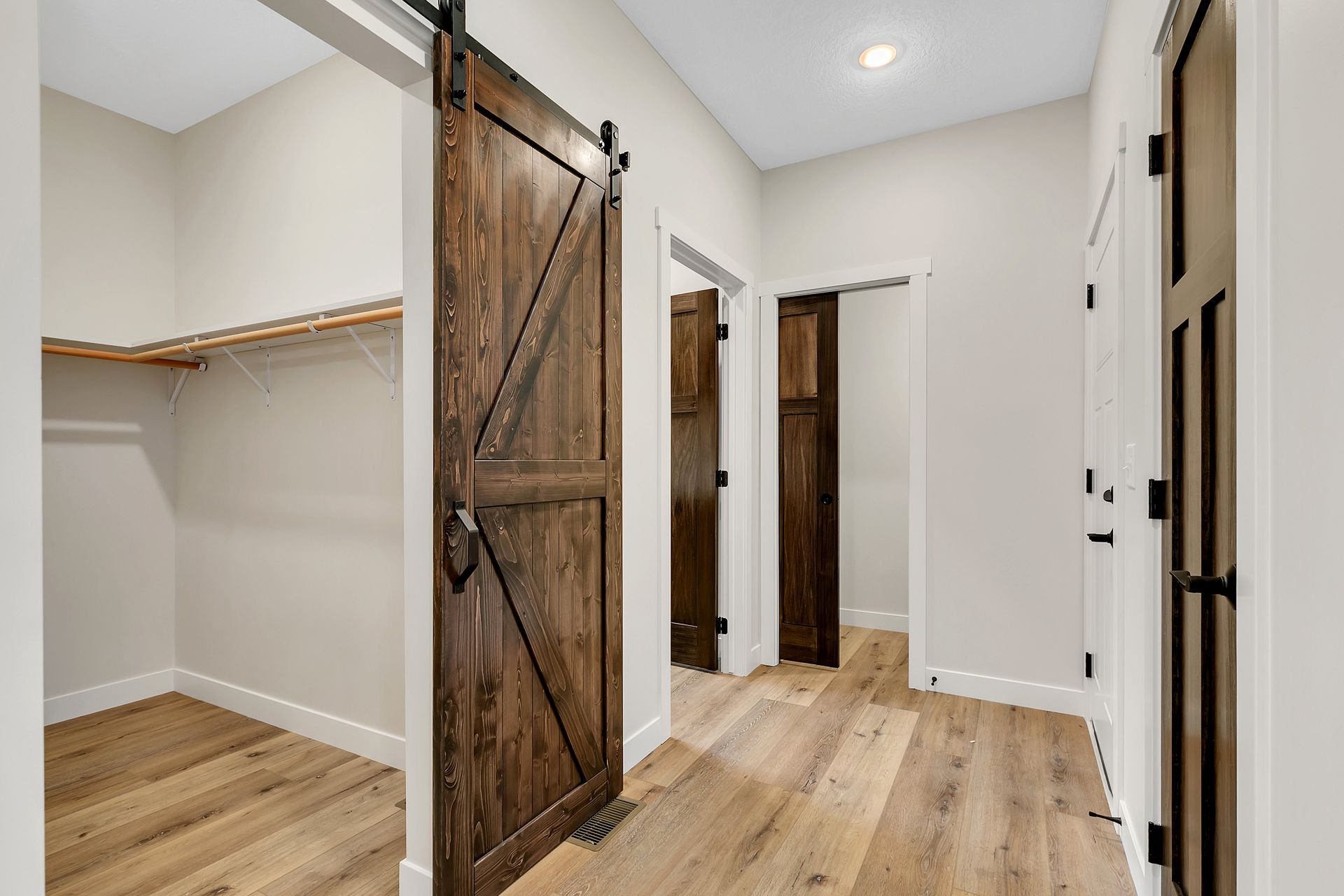 A walk in closet with sliding barn doors and hardwood floors.