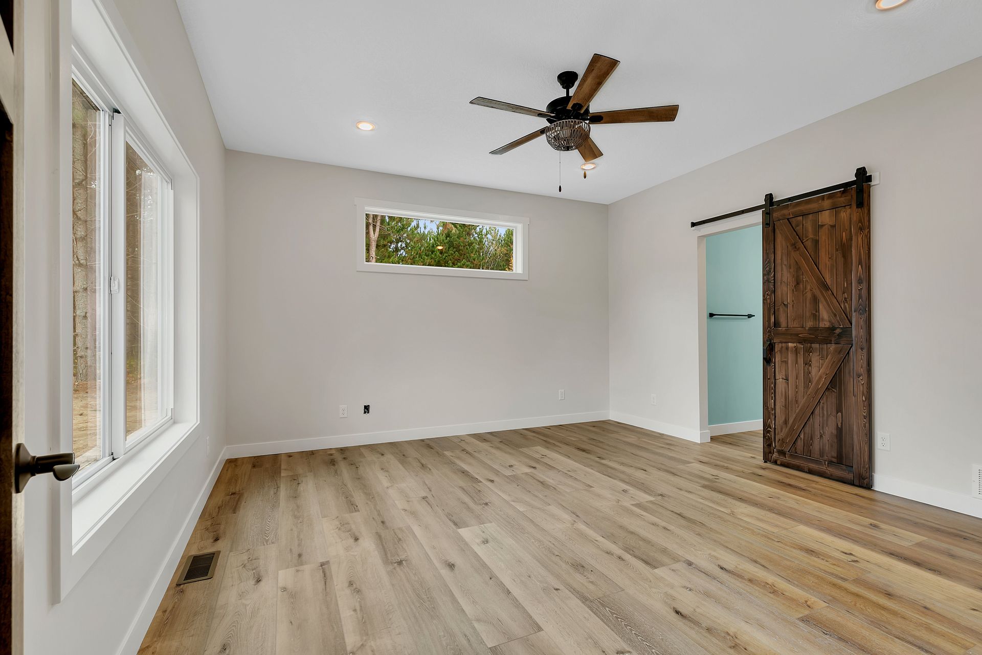 There is a ceiling fan in the room and a sliding barn door.