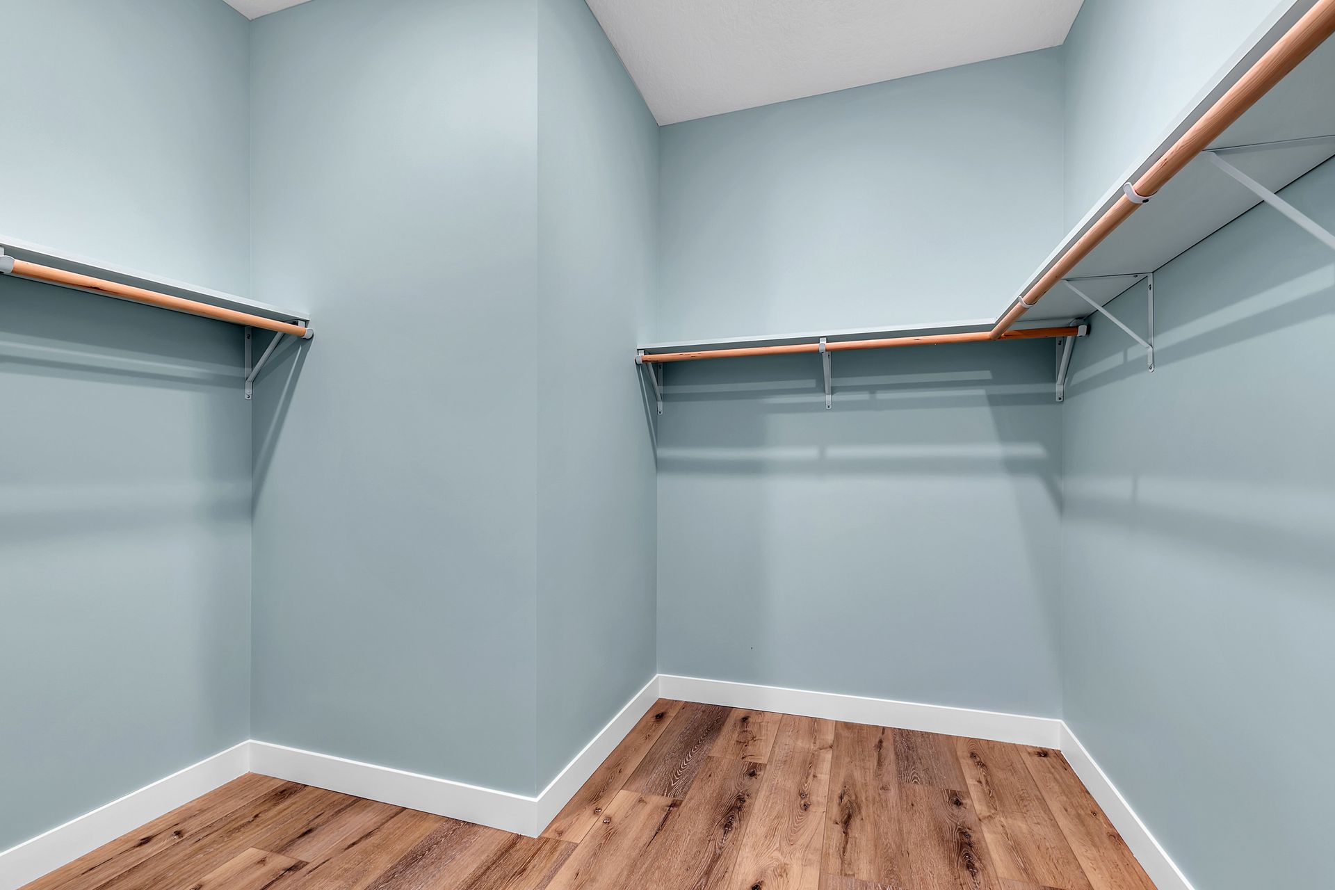 An empty walk in closet with wooden floors and blue walls.