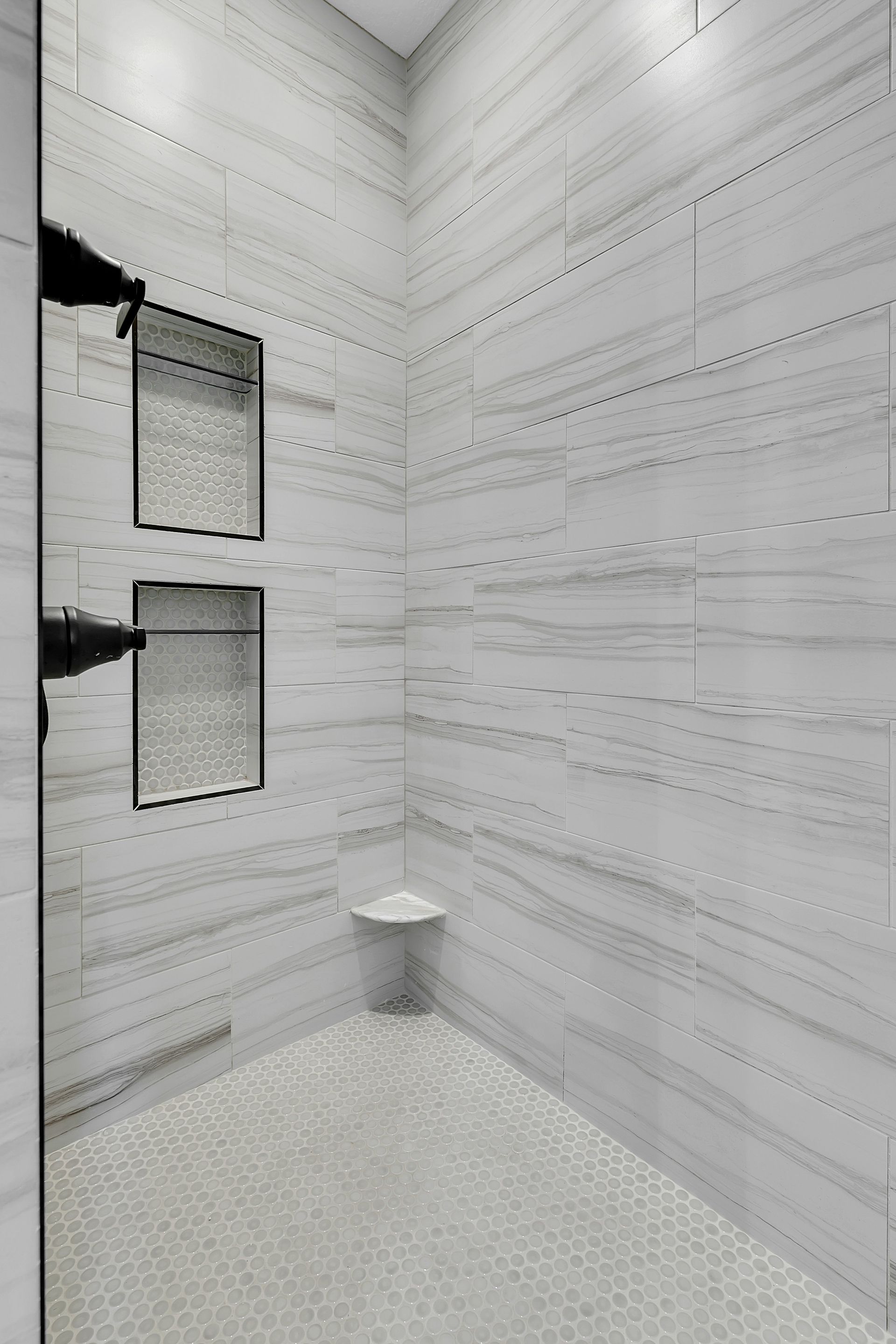A bathroom with marble tiles and a walk in shower.