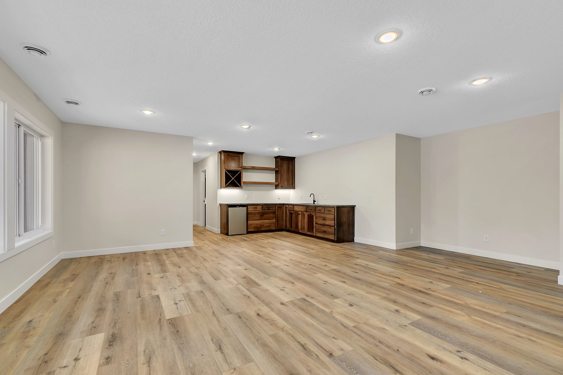 A large empty room with hardwood floors and white walls.