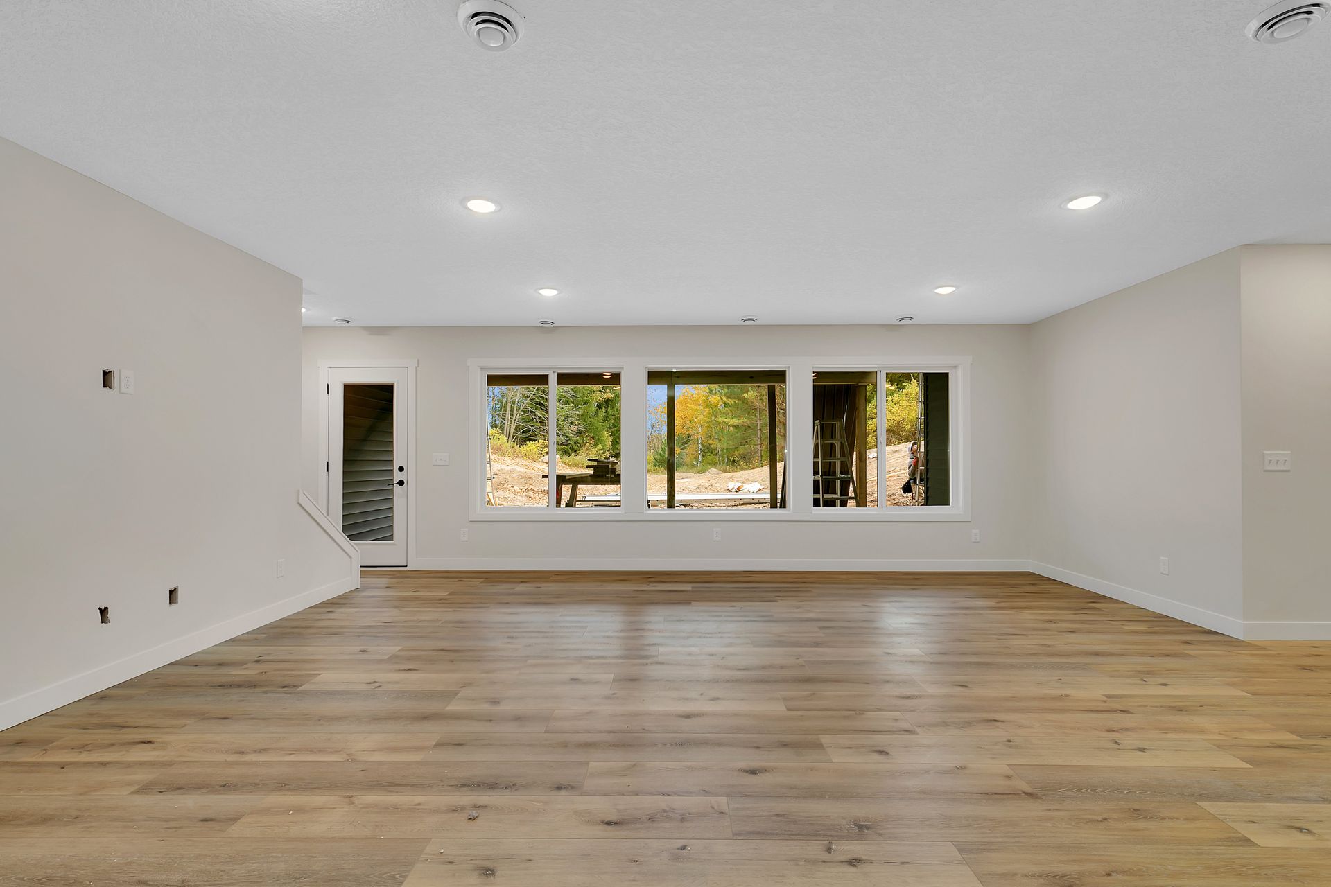 A large empty room with hardwood floors and white walls.