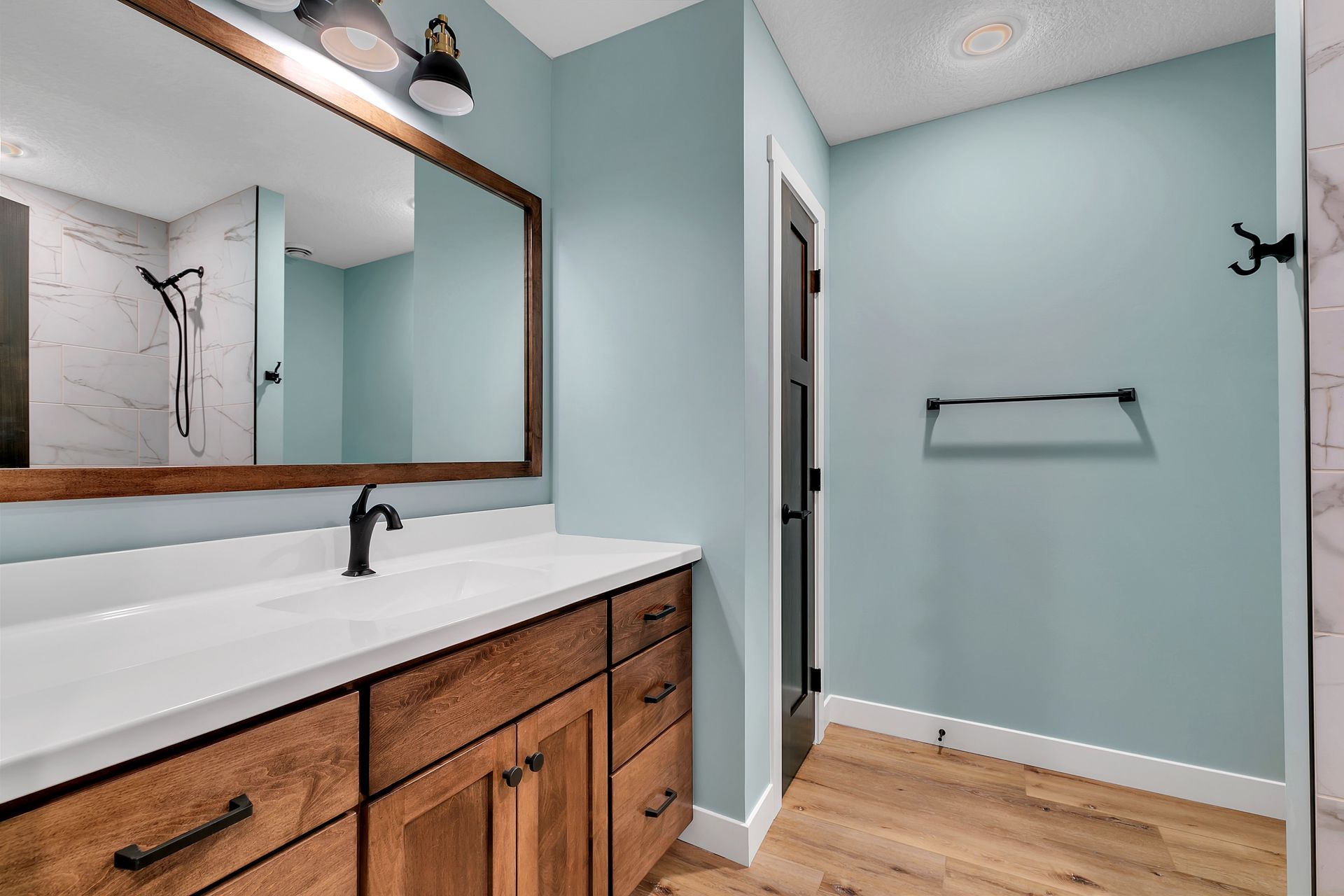 A bathroom with two sinks , a large mirror and a walk in shower.