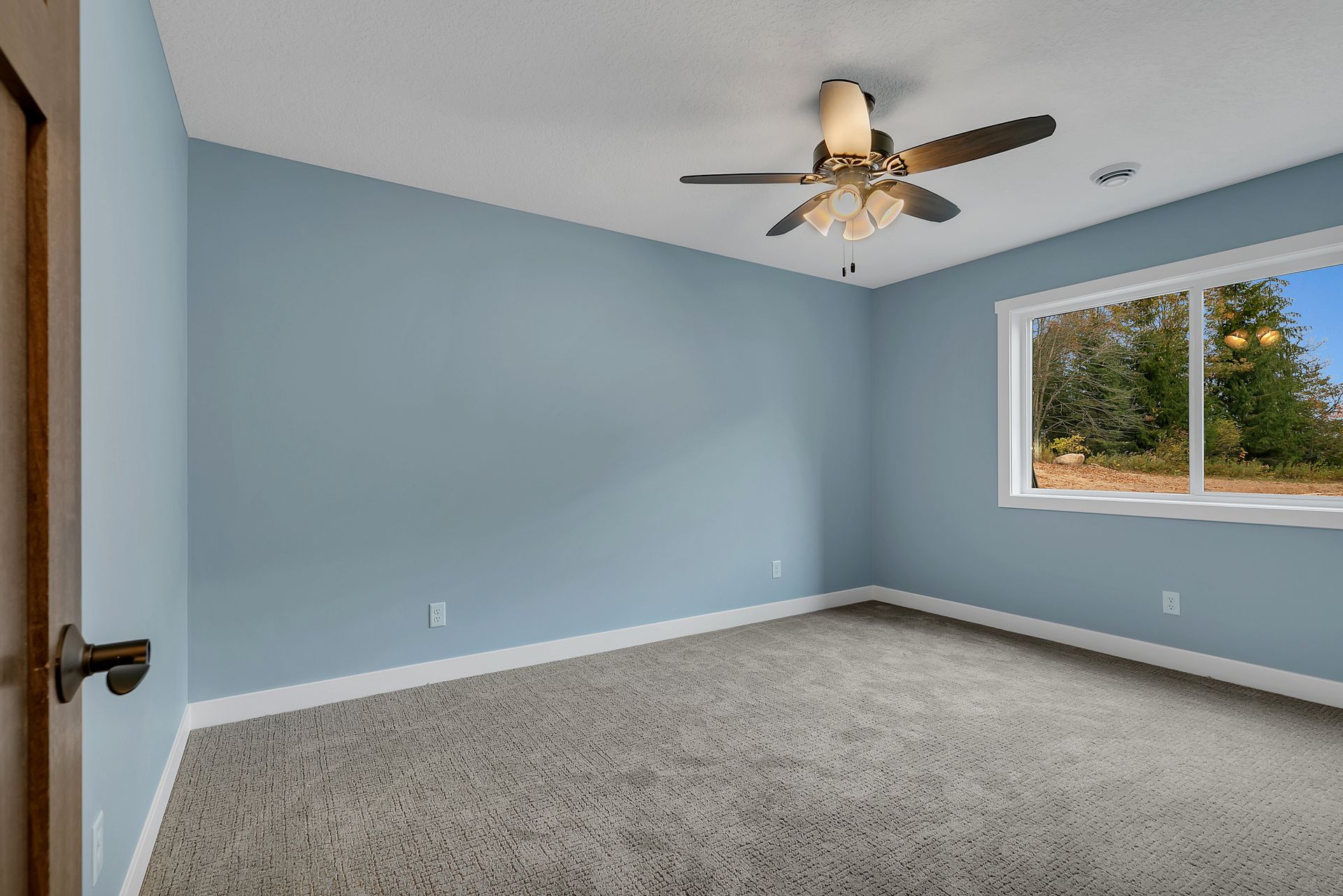 An empty bedroom with a ceiling fan and a window.