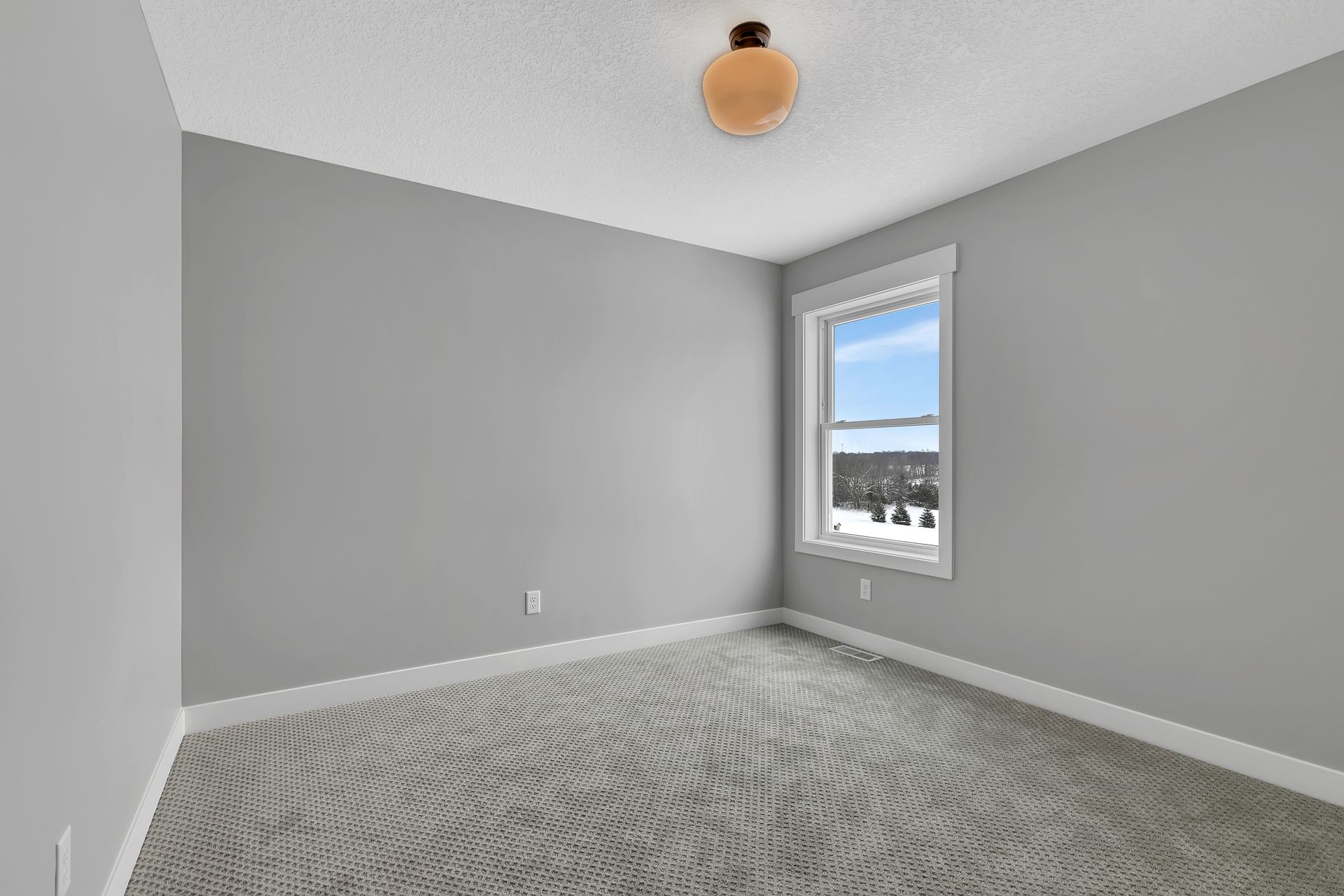 An empty bedroom with gray walls and a window.