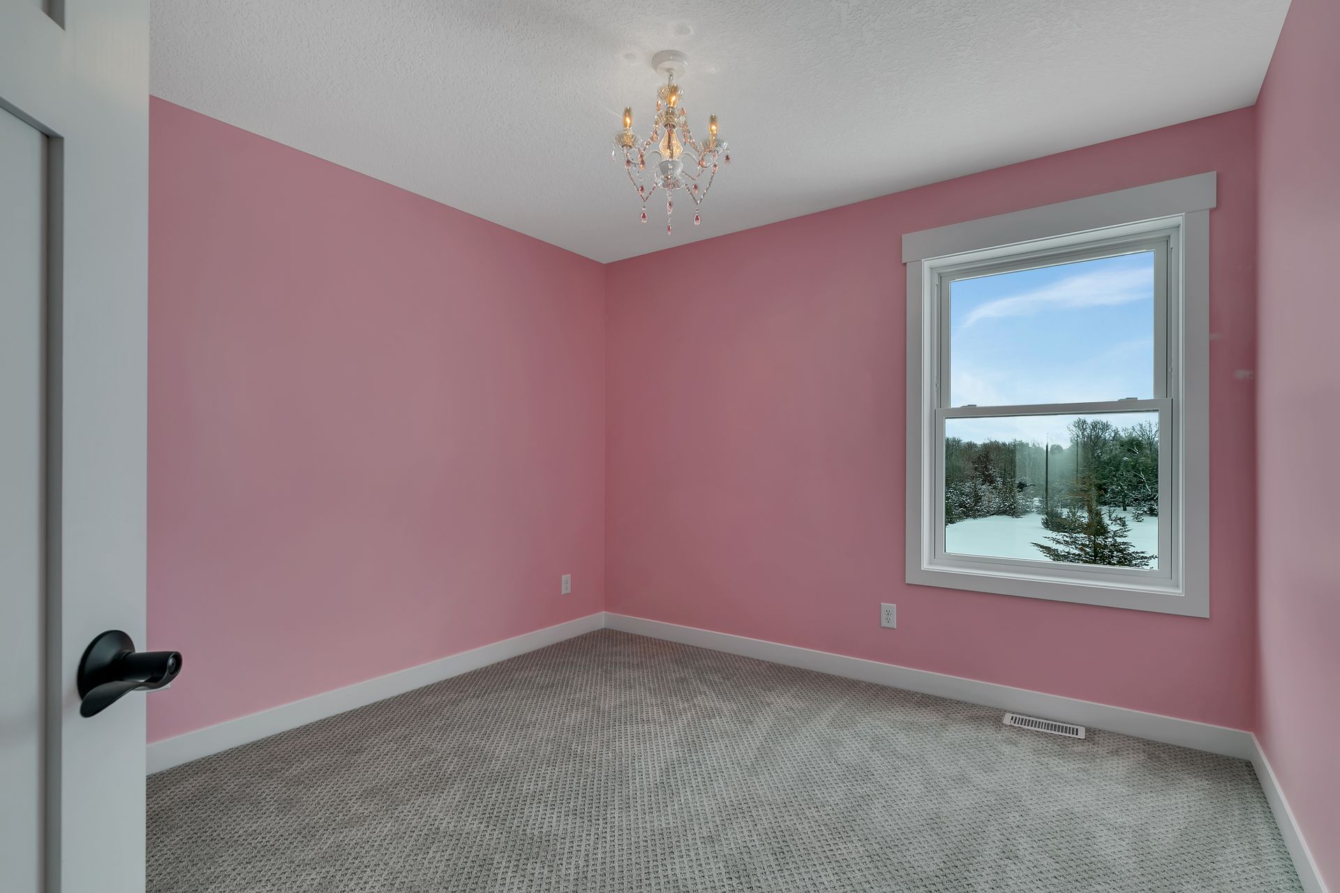 An empty bedroom with pink walls and a window.