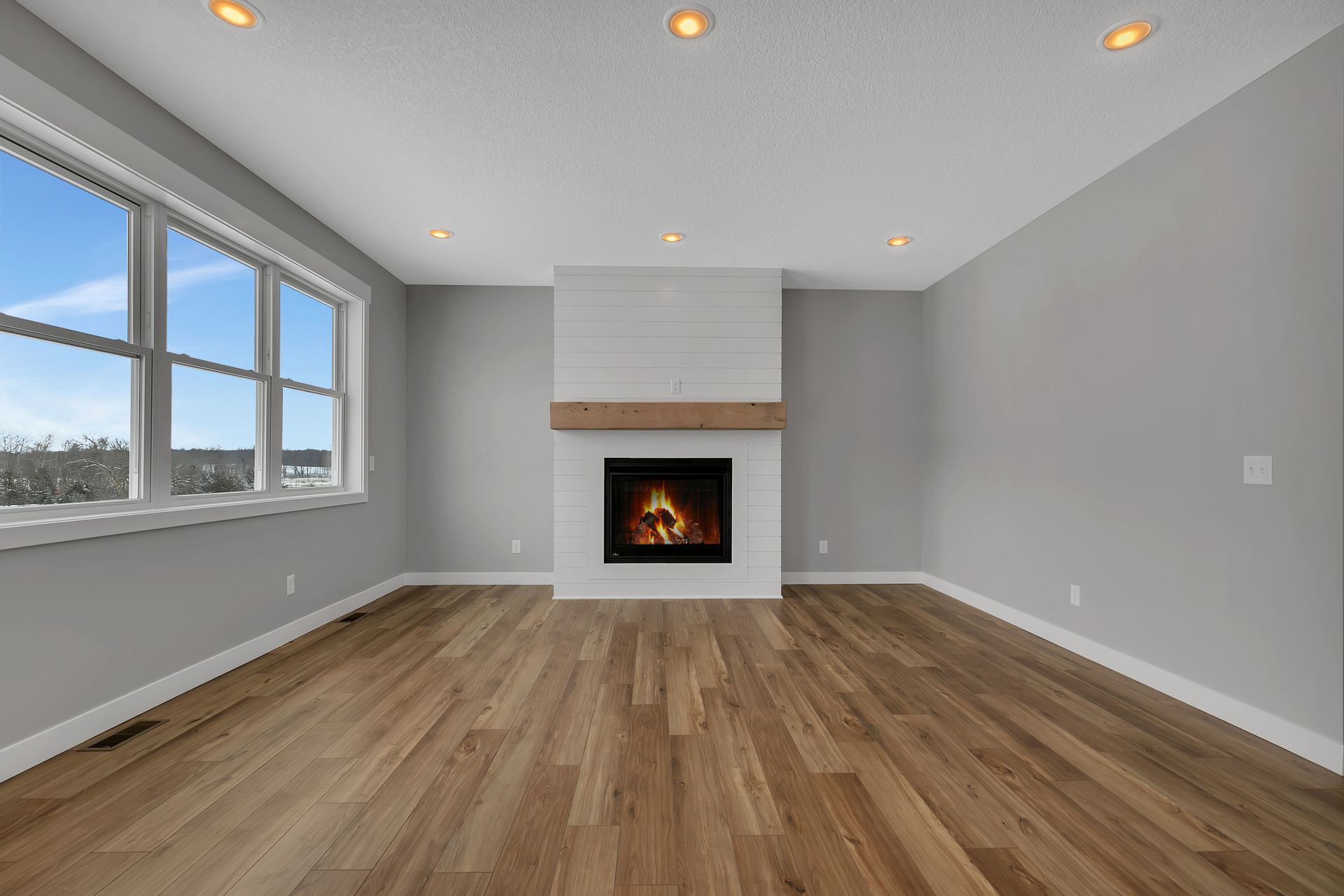 An empty living room with hardwood floors and a fireplace.