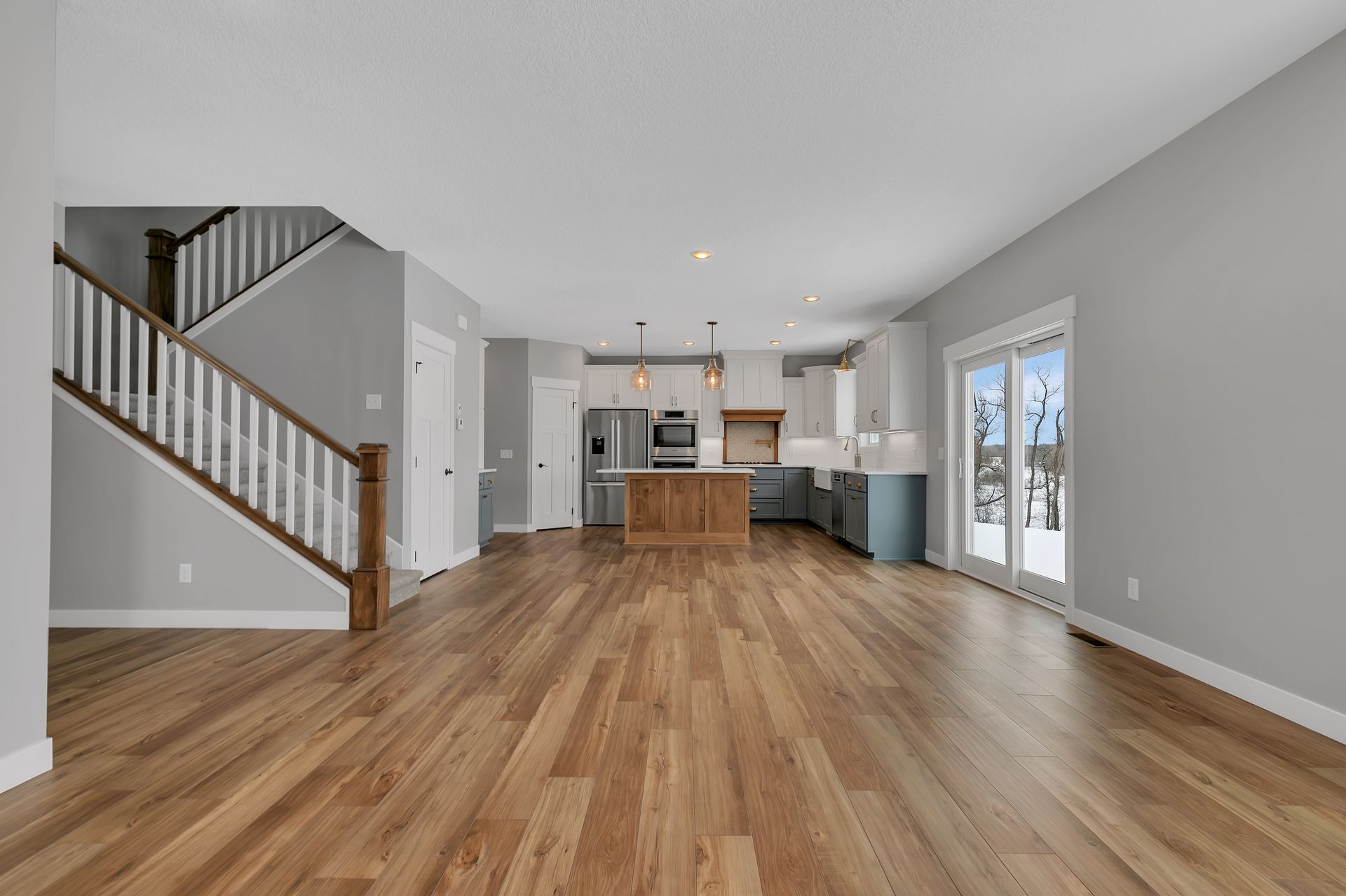 A large empty room with hardwood floors and a kitchen.