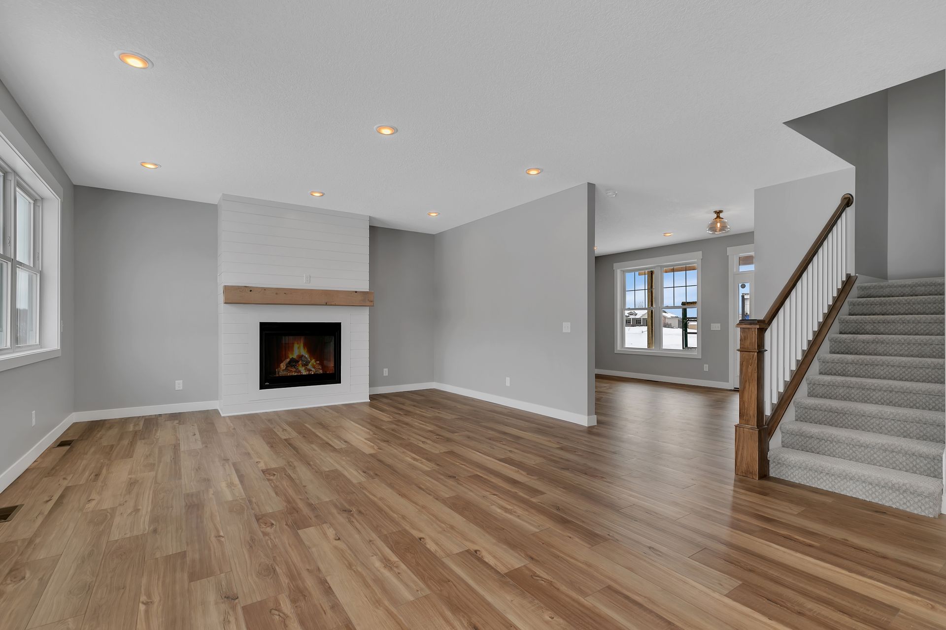 An empty living room with hardwood floors , a fireplace and stairs.