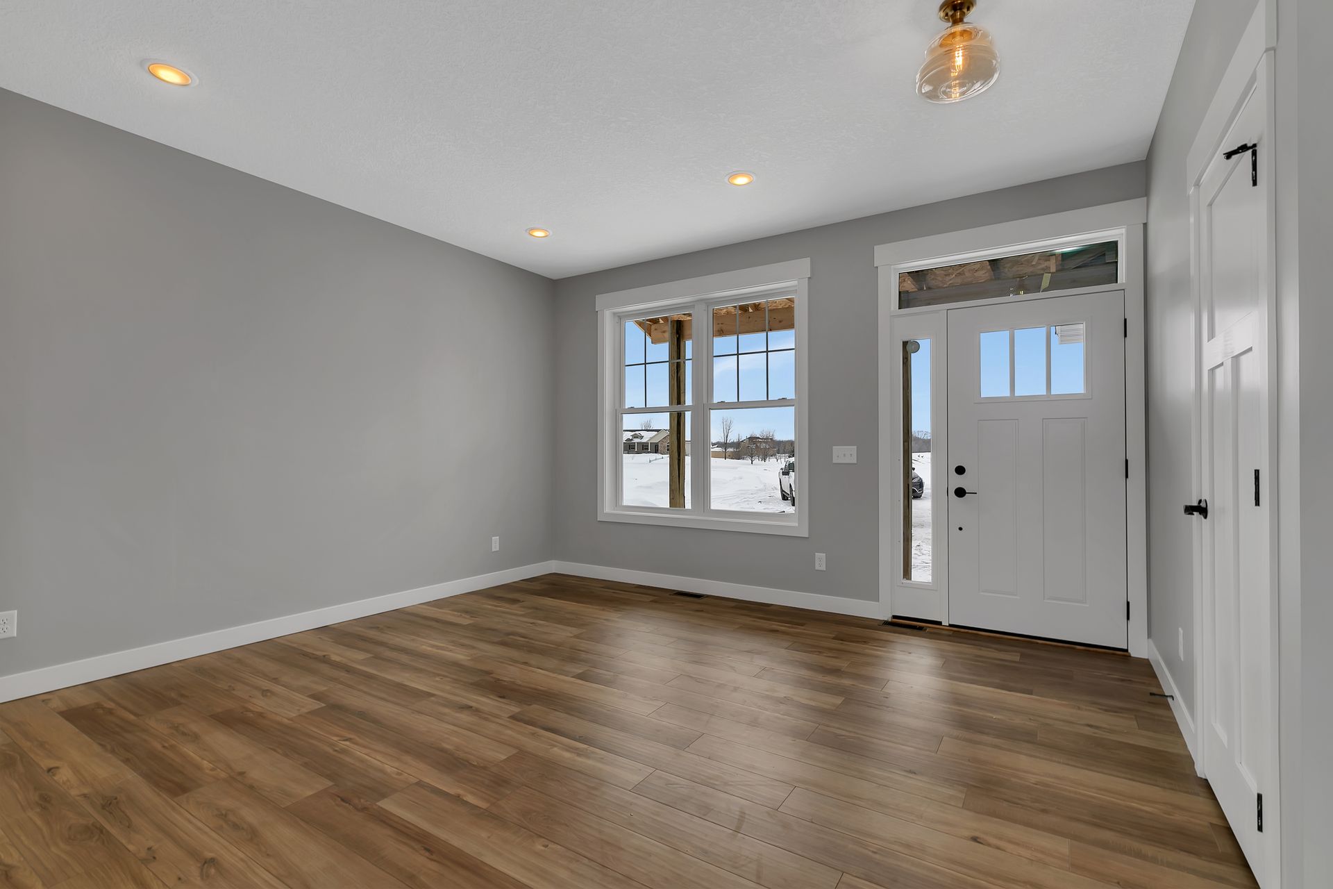 An empty living room with hardwood floors and a white door.