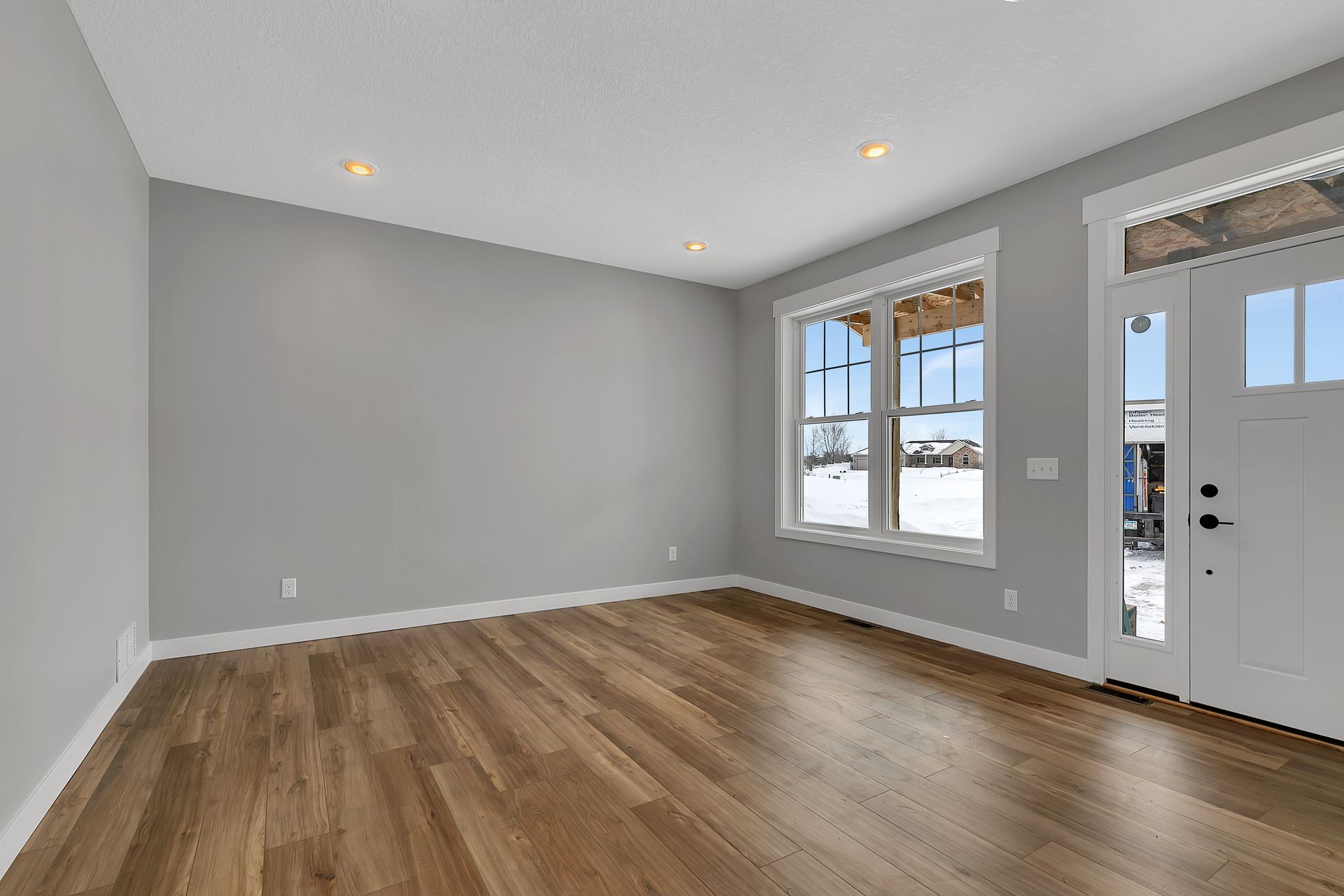 An empty living room with hardwood floors and gray walls.