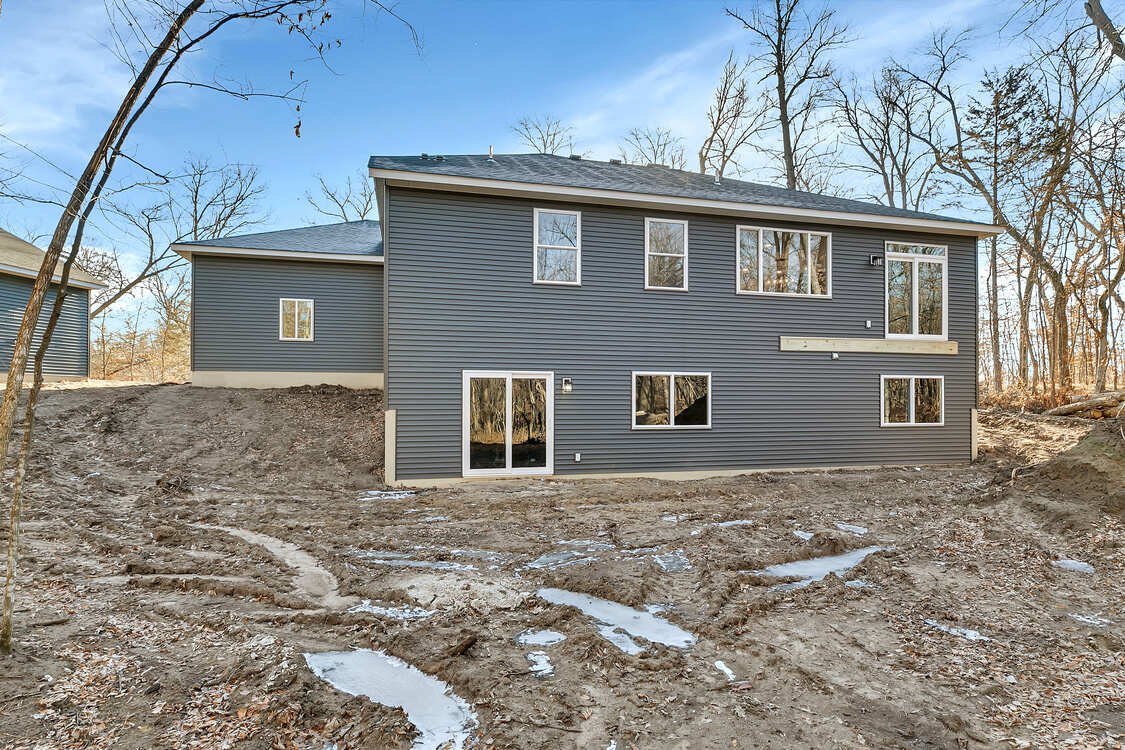 A large house with a lot of windows is sitting on top of a dirt hill.