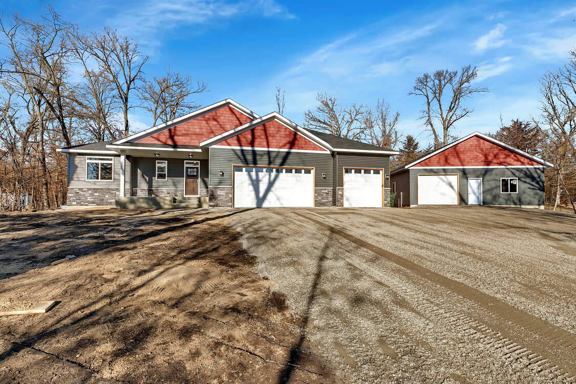 A large house with a red roof is sitting on top of a dirt road.