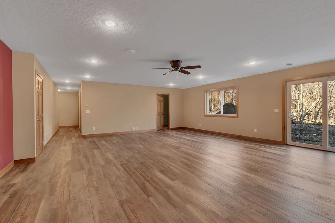 An empty living room with hardwood floors and a ceiling fan.