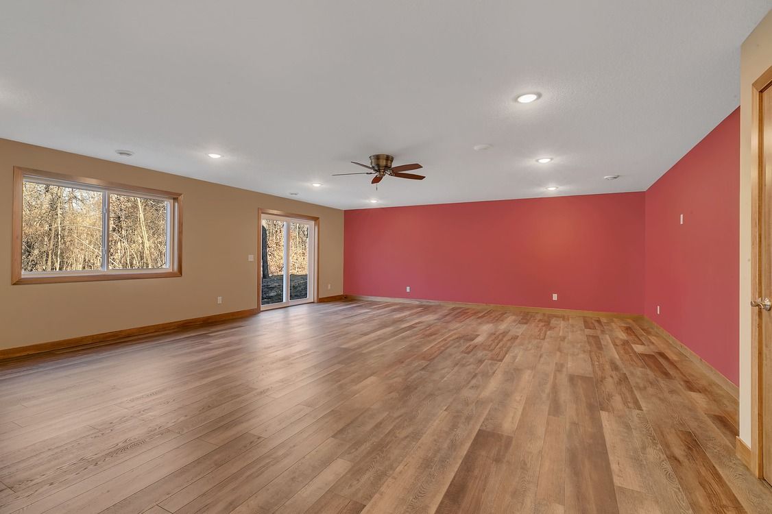 A large empty room with hardwood floors and red walls.