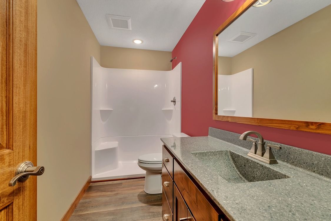 A bathroom with a sink , toilet , shower and mirror.
