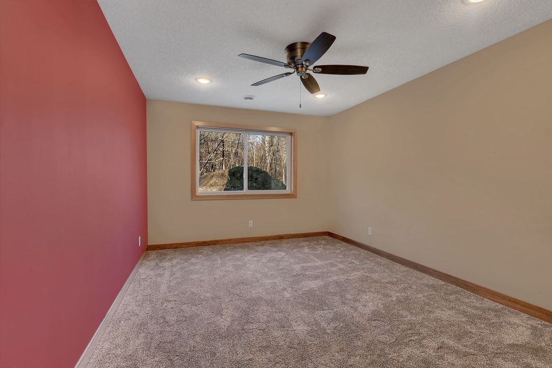An empty room with a ceiling fan and a window.