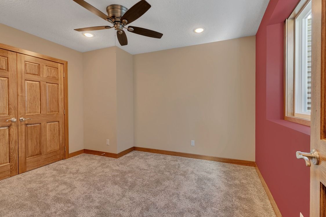 An empty room with a ceiling fan and a window.