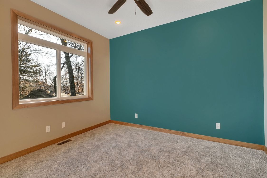 An empty bedroom with a blue wall and a ceiling fan.
